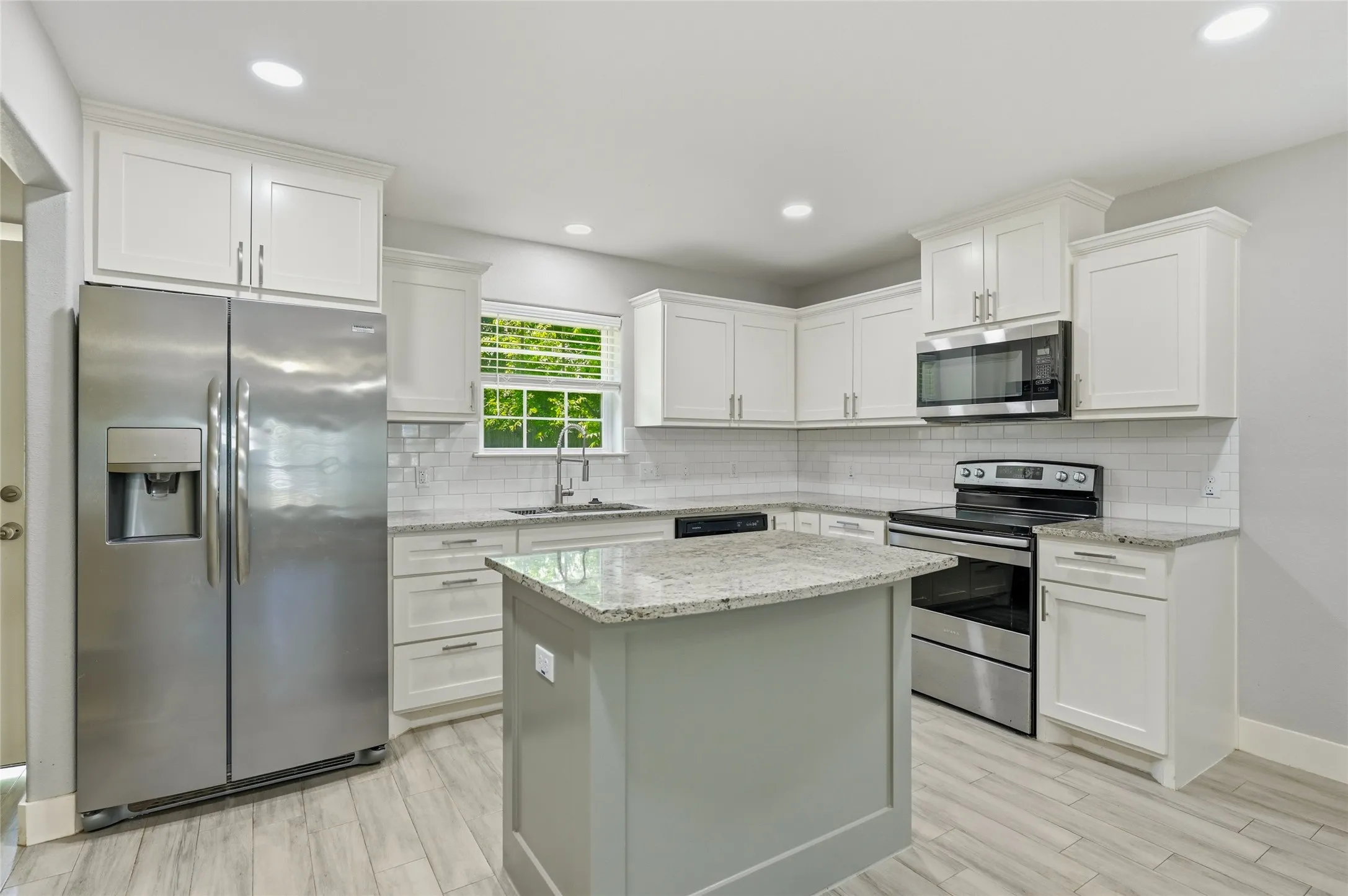 Kitchen featuring white cabinetry, light granite-style countertops, stainless steel appliances, a subway tile backsplash, and ceramic tile flooring
