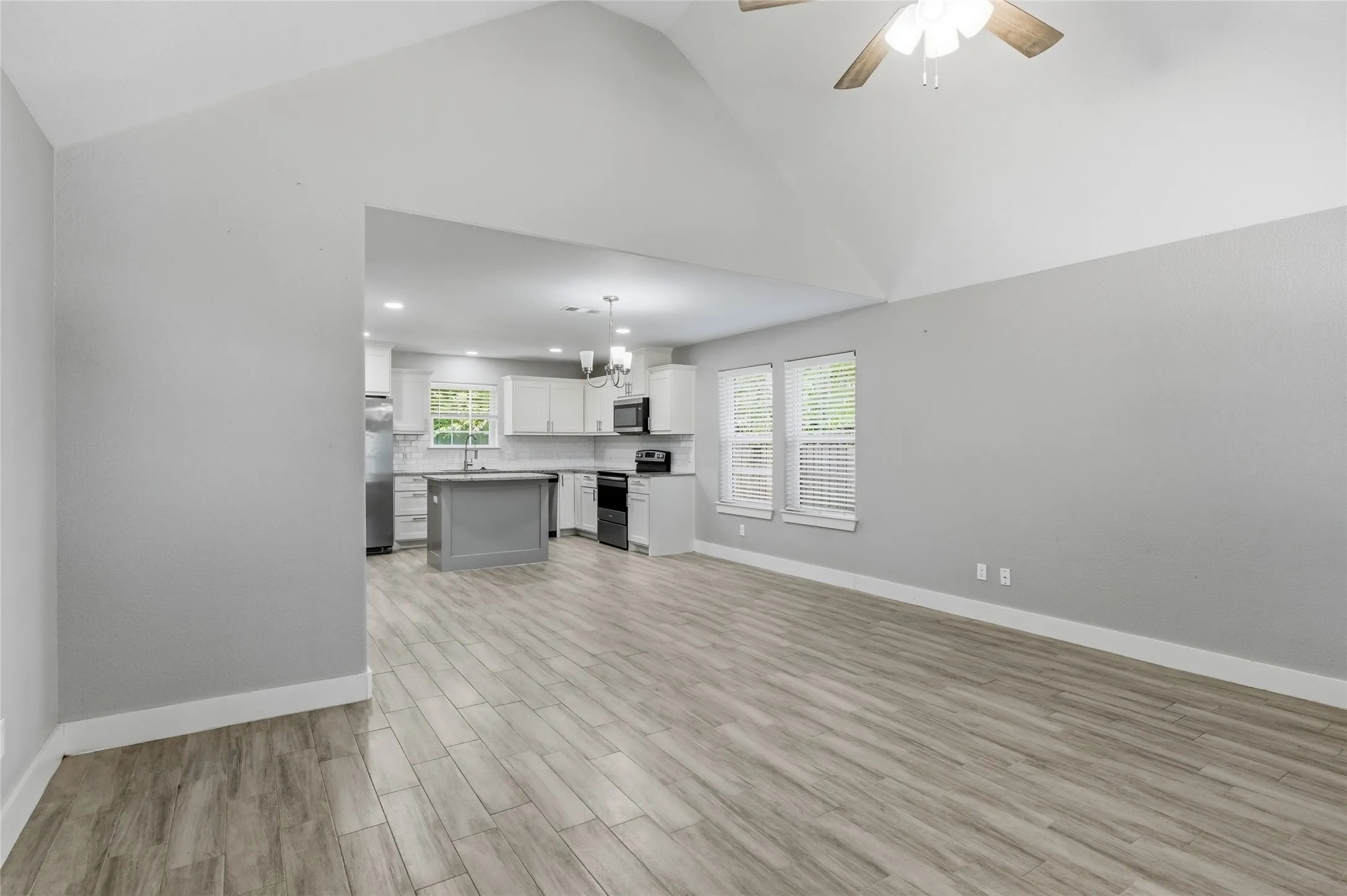 Spacious living area featuring vaulted ceilings, ceramic tile flooring, and multiple windows