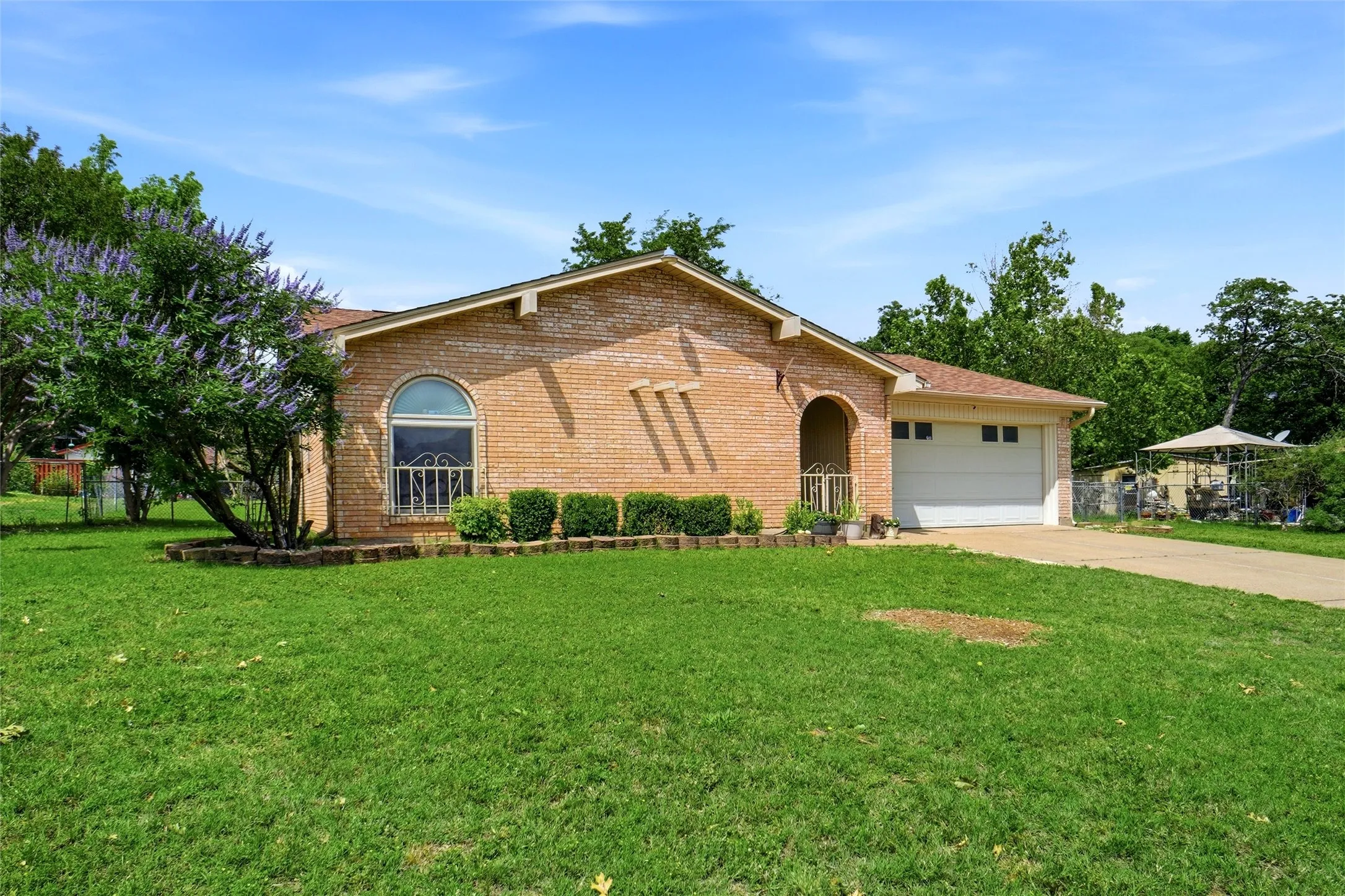 Brick exterior with an arched entry, an arched window, a two-car garage, and a concrete driveway