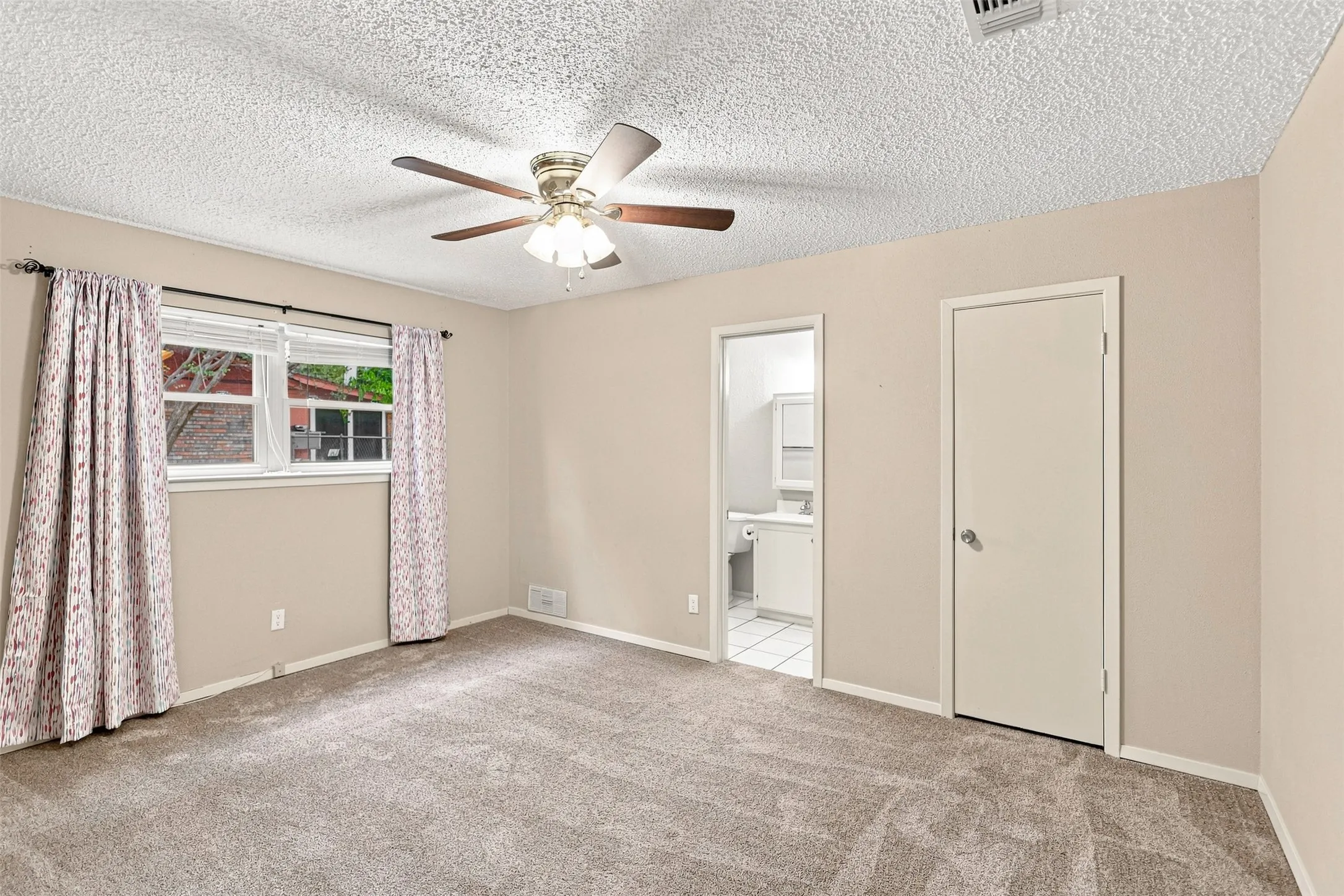 Carpeted room with a ceiling fan, white trim, and a window