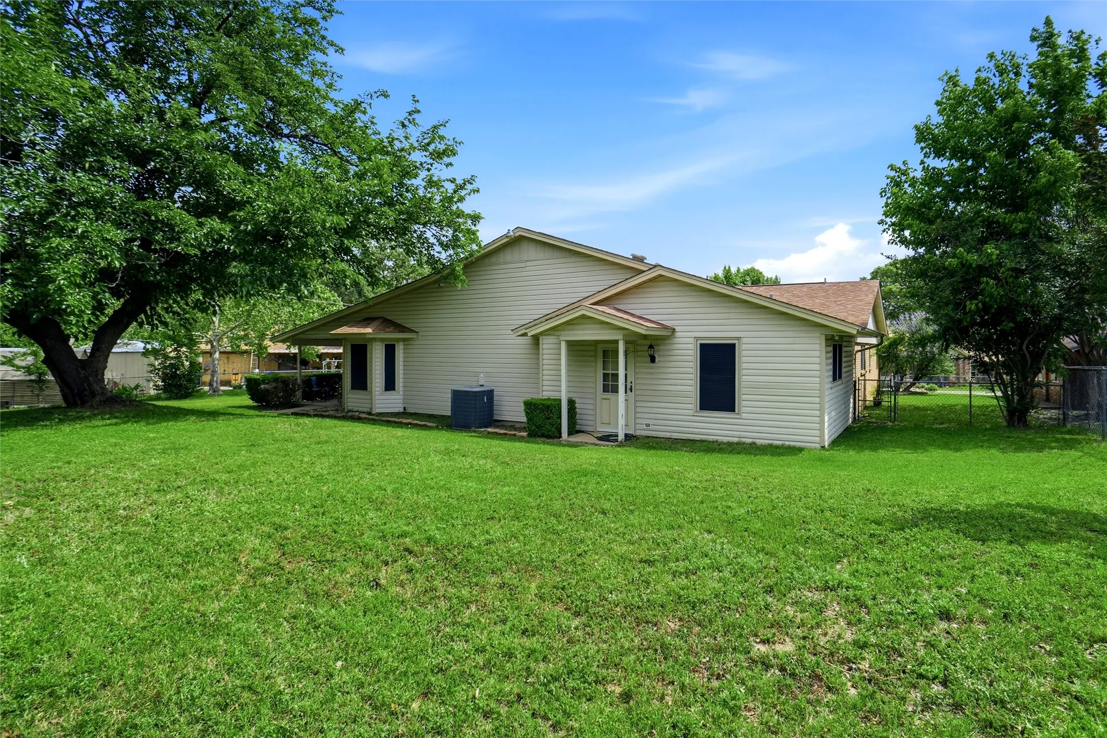 Expansive backyard featuring a manicured lawn, established trees, and durable siding
