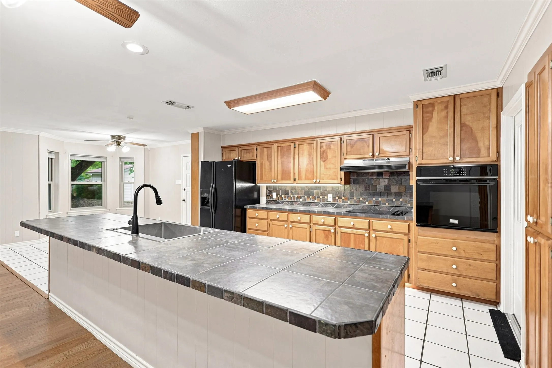 Kitchen with wood cabinetry, integrated oven, and a tiled backsplash