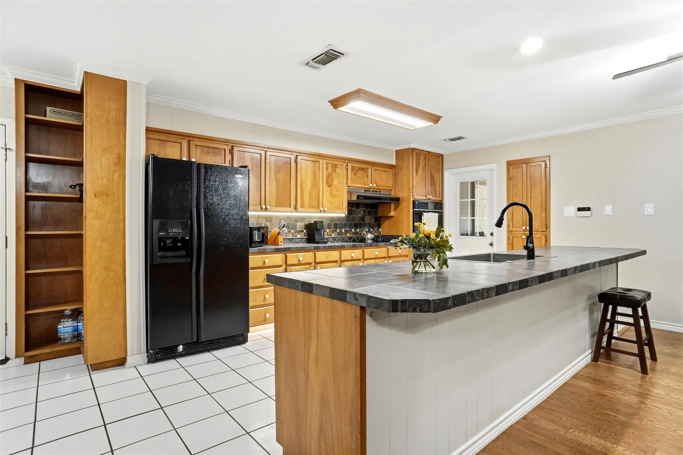 Kitchen featuring a central island with a built-in sink and seating overhang