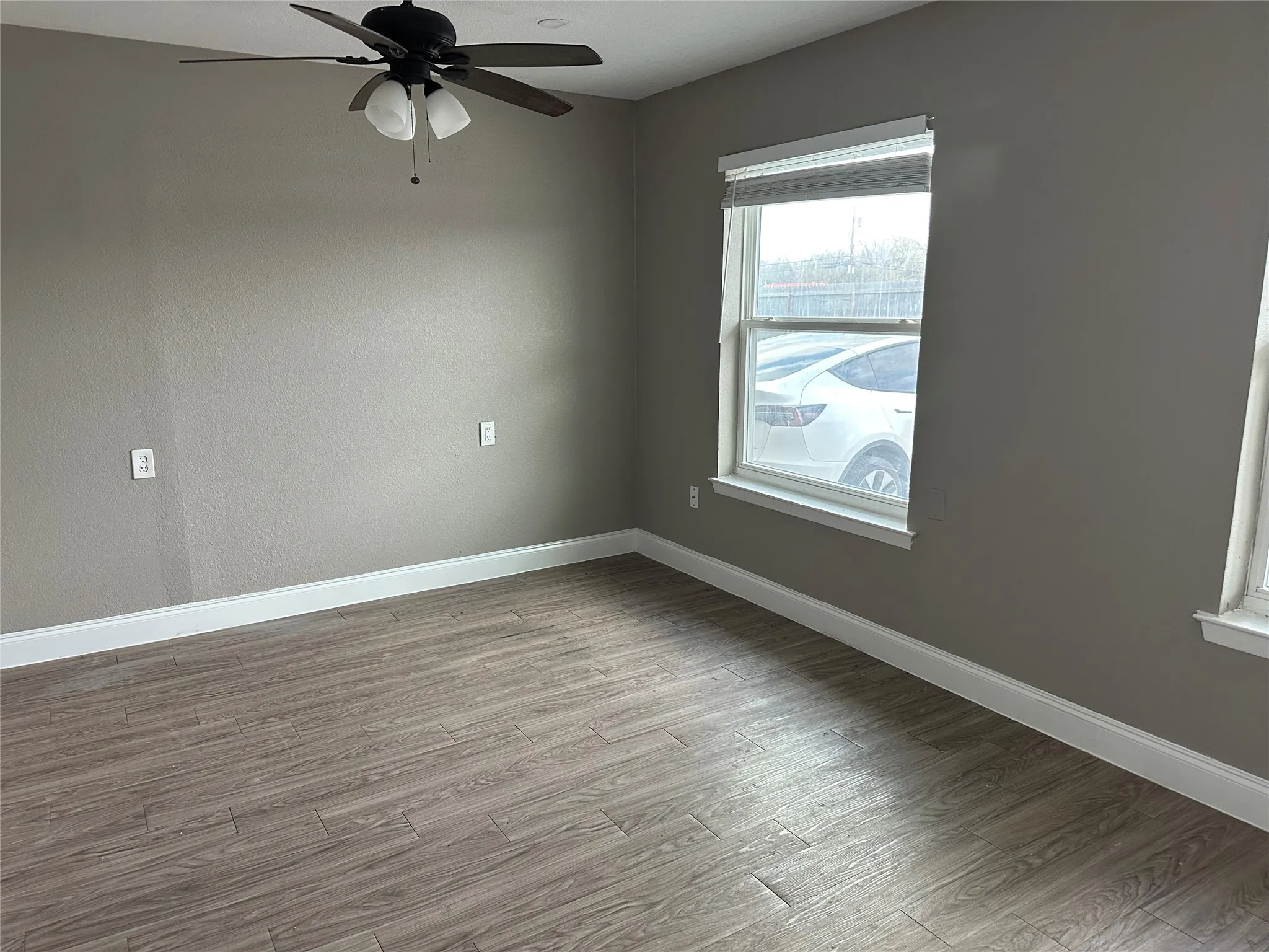 Interior space featuring wood-finish flooring, a ceiling fan with integrated lighting, and neutral wall tones