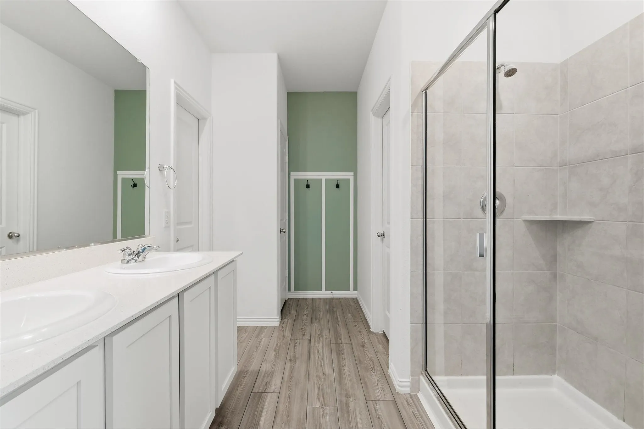 Ensuite primary bathroom features dual sinks, generous cabinet space, linen closet, large shower, and roomy walk-in closet