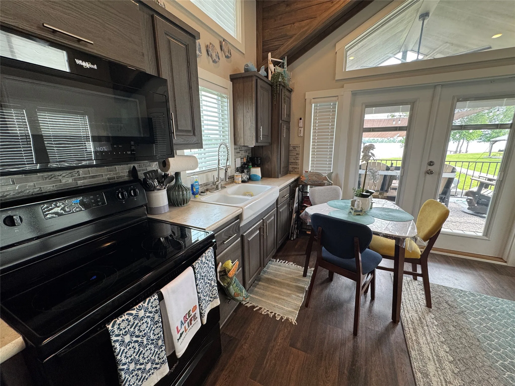 Kitchen featuring dark wood-finish cabinetry, a black appliance suite, and a white farmhouse sink