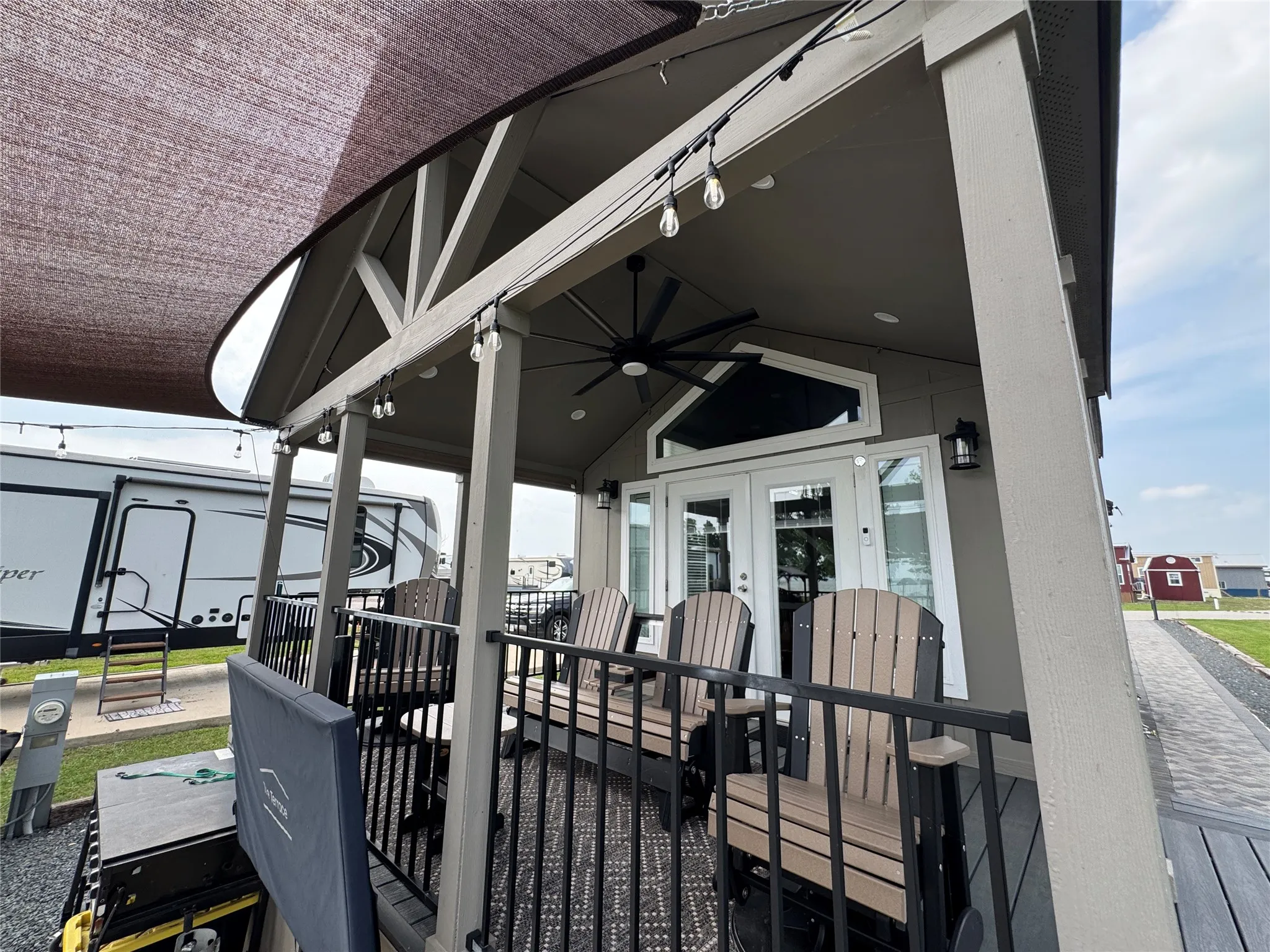 Covered porch with exposed rafters and a ceiling fan