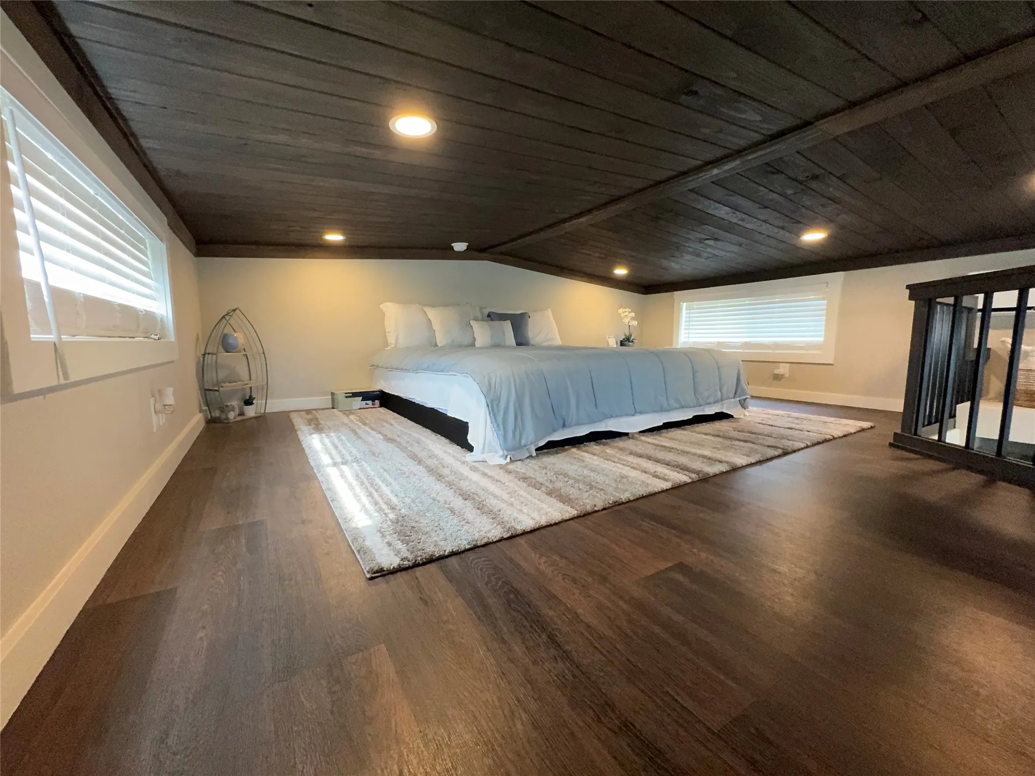Expansive loft space featuring dark wood-finish flooring, a dark wood plank ceiling with recessed lighting, and multiple windows with white blinds