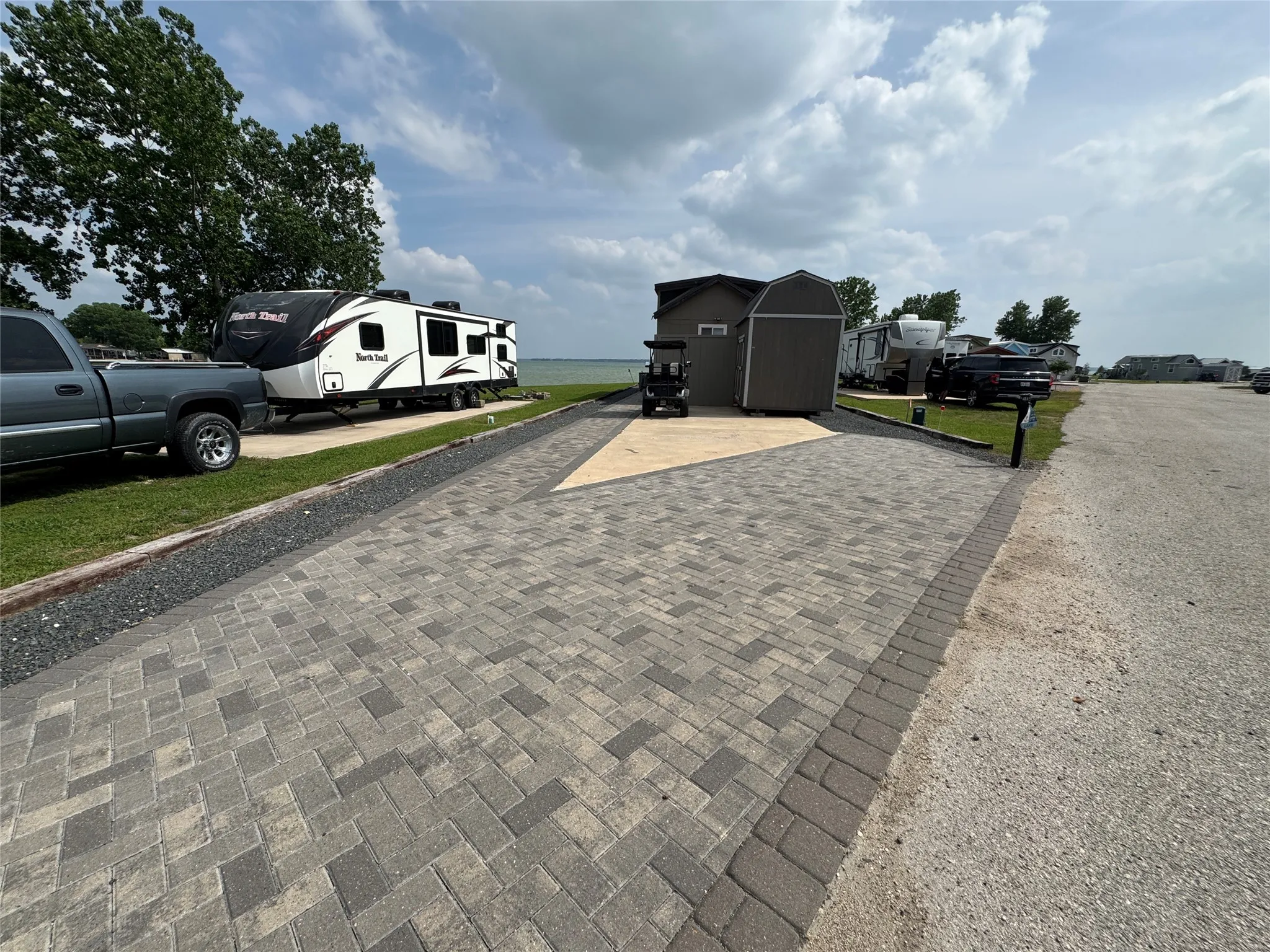 Paved herringbone pattern driveway featuring a dark paver border and gravel accents