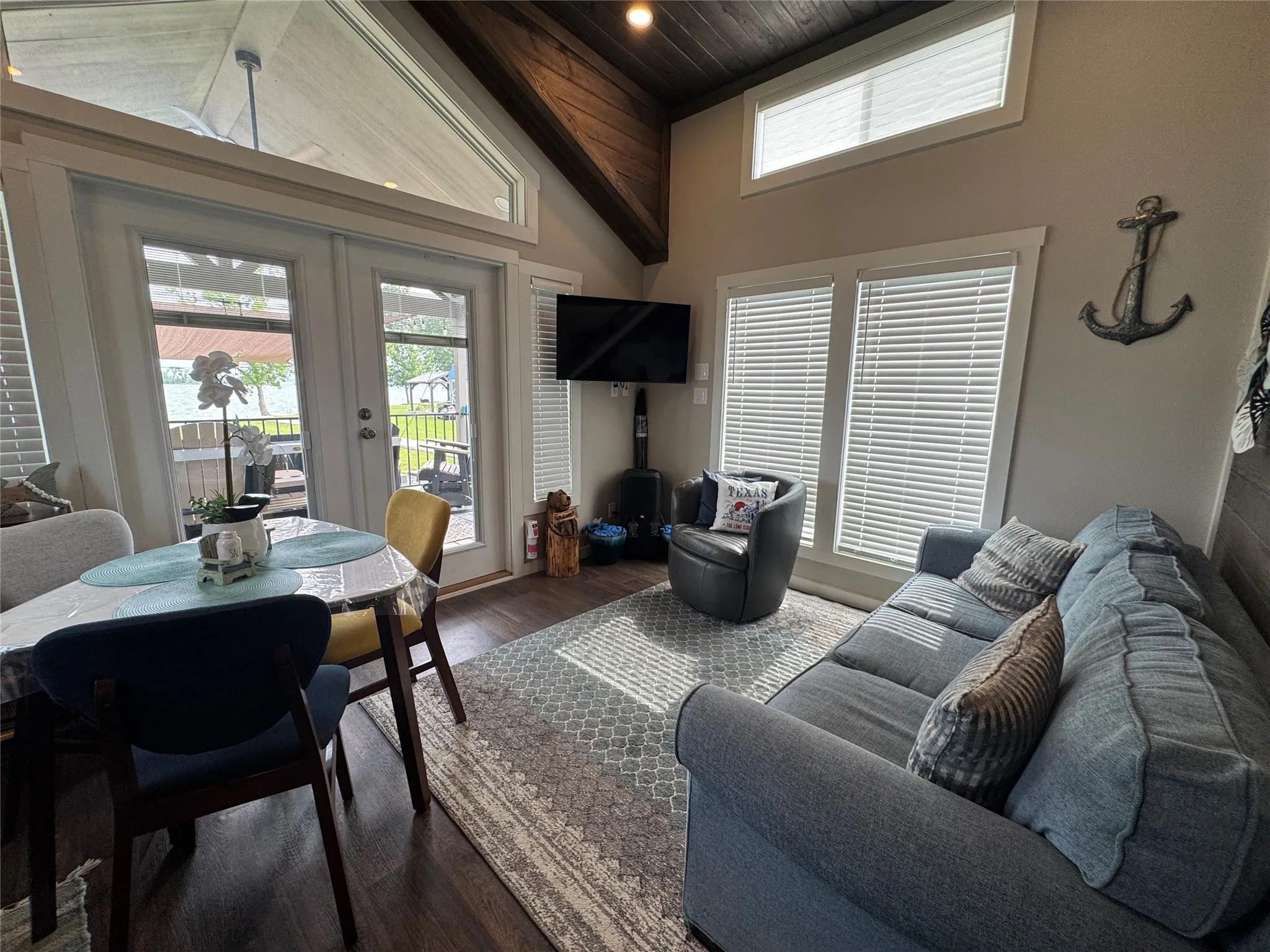 Living area featuring a vaulted ceiling with dark wood-finish, dual French doors, a transom window, and wood-finish flooring