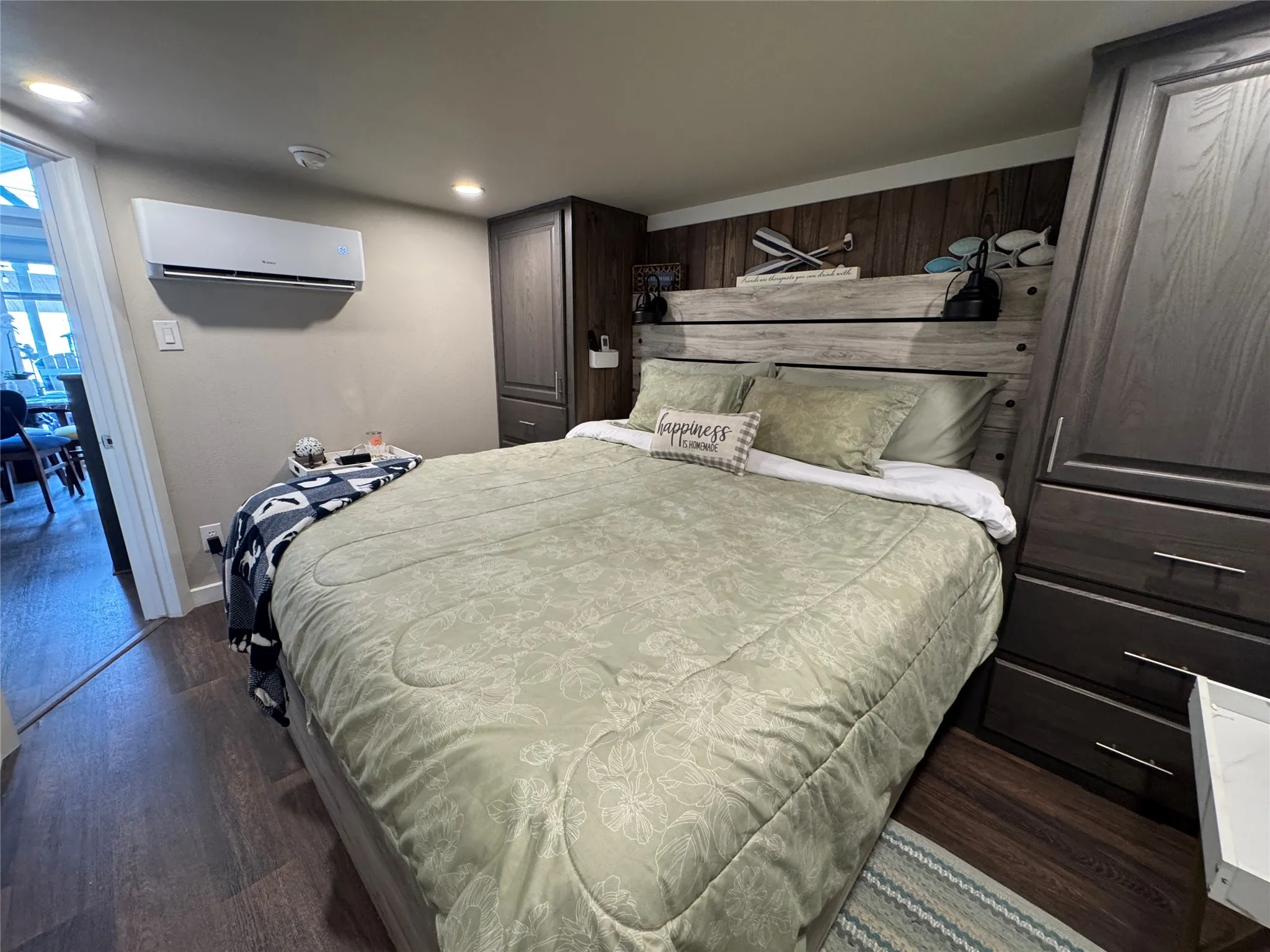 Bedroom with wood-finish flooring, recessed ceiling lighting, and a wall-mounted mini-split system