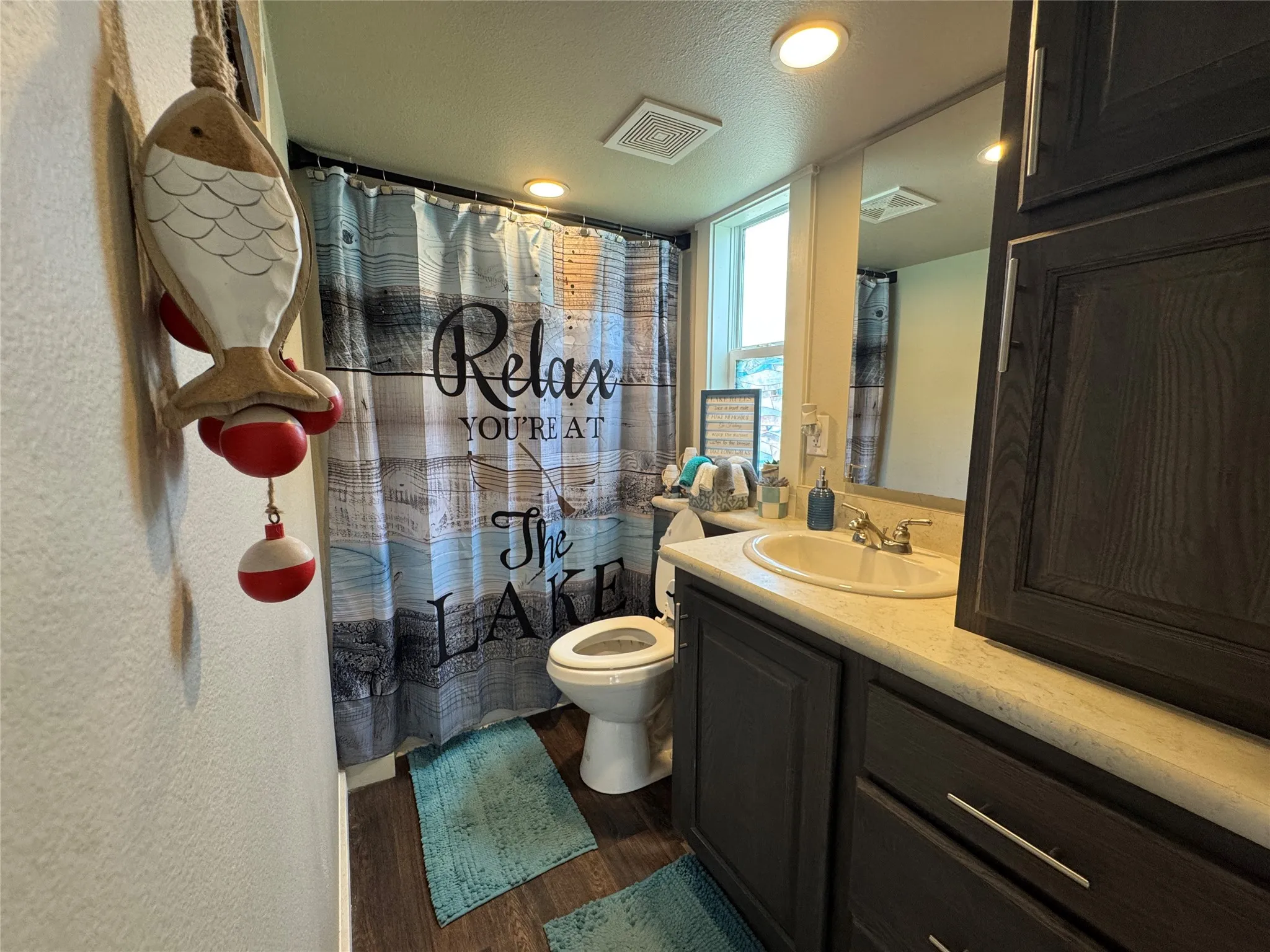 Bathroom featuring a dark wood-finish vanity with a light countertop and an integrated sink