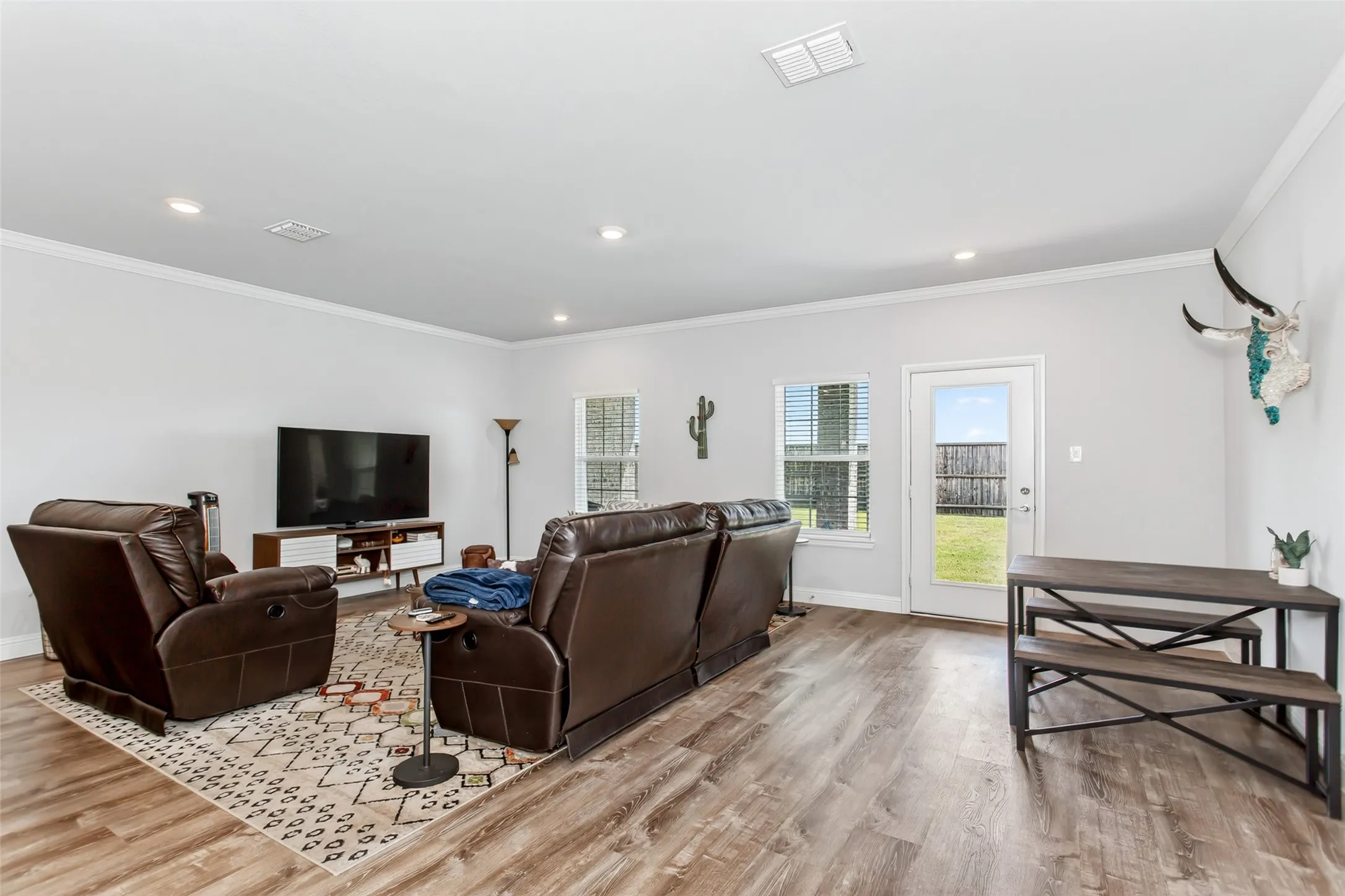 Bright and inviting living space featuring durable wood-look flooring, oversized windows, and easy access to the covered patio and backyard.