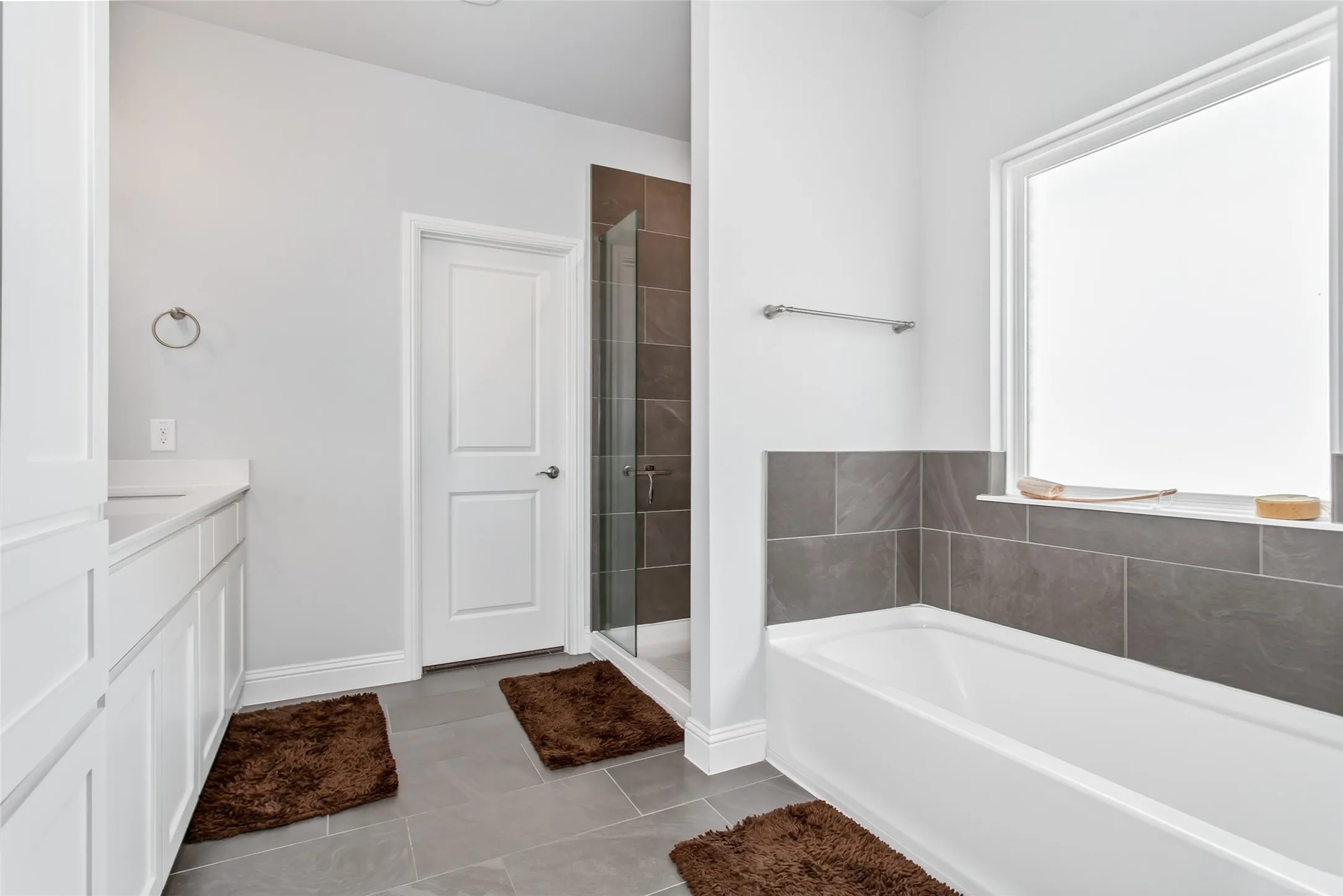 Luxurious ensuite bathroom offering separate vanities, abundant storage, a large walk-in closet, soaking tub, and spacious frameless glass shower for a true retreat feel.