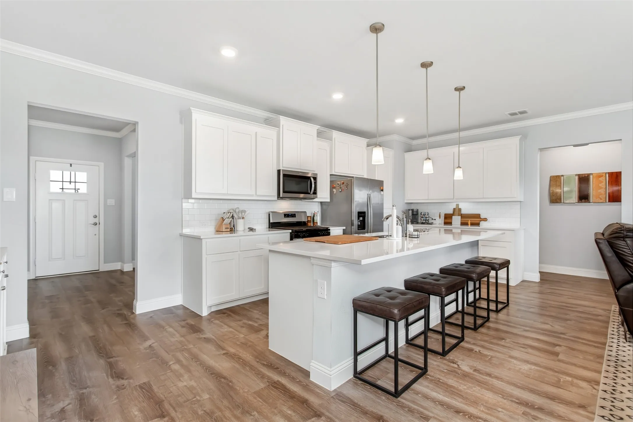 Bright open-concept kitchen featuring an oversized island, quartz countertops, stainless steel appliances, and abundant cabinet space.
