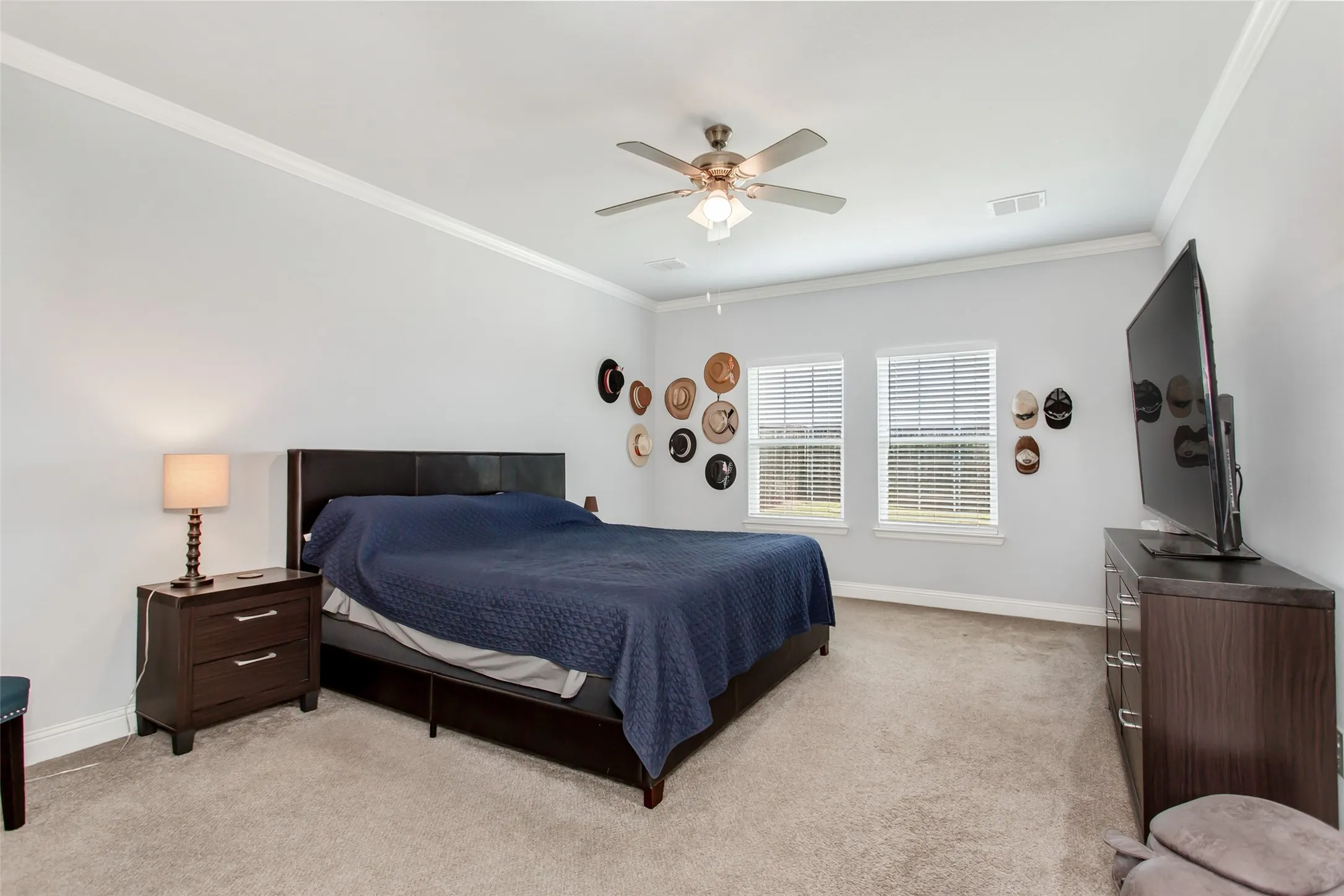 Relaxing primary bedroom retreat with oversized layout, neutral tones, ceiling fan, and large windows that create a bright and airy feel.