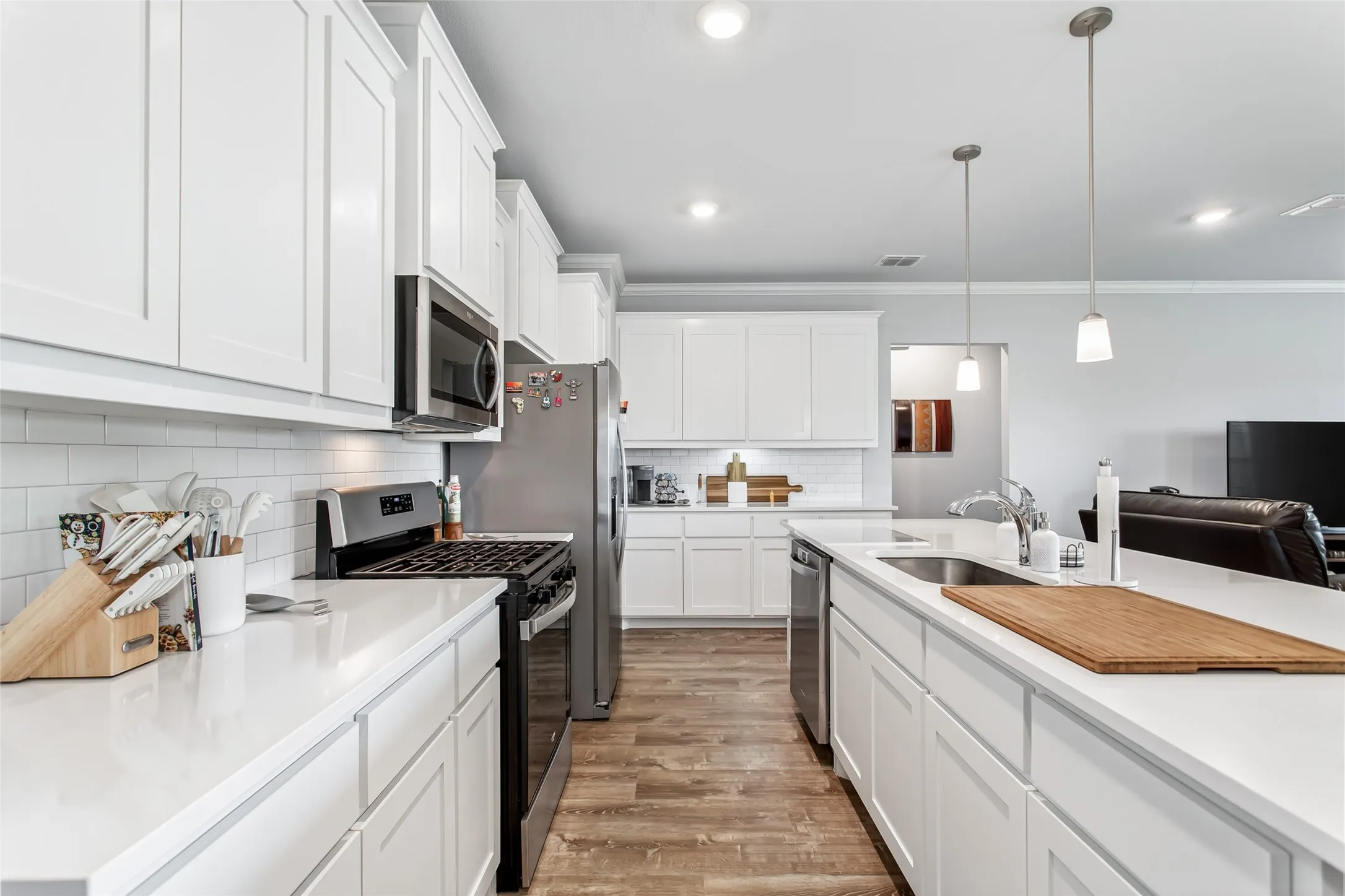Modern finishes shine throughout with crisp white cabinetry, subway tile backsplash, pendant lighting, and sleek stainless steel appliances.