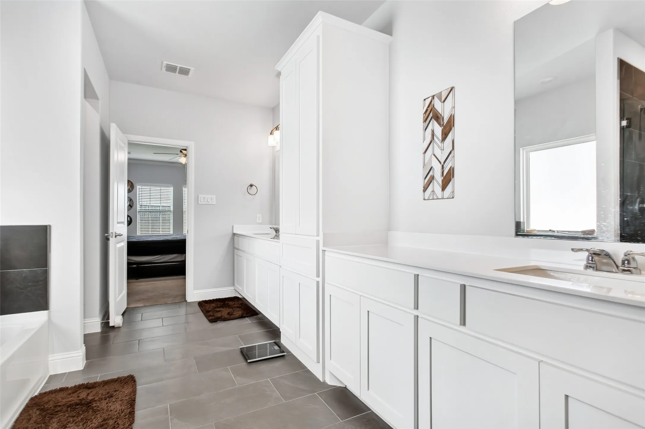 Bright and airy primary bath with modern finishes, dual sinks, oversized mirrors, generous cabinetry, separate shower, and relaxing garden tub.