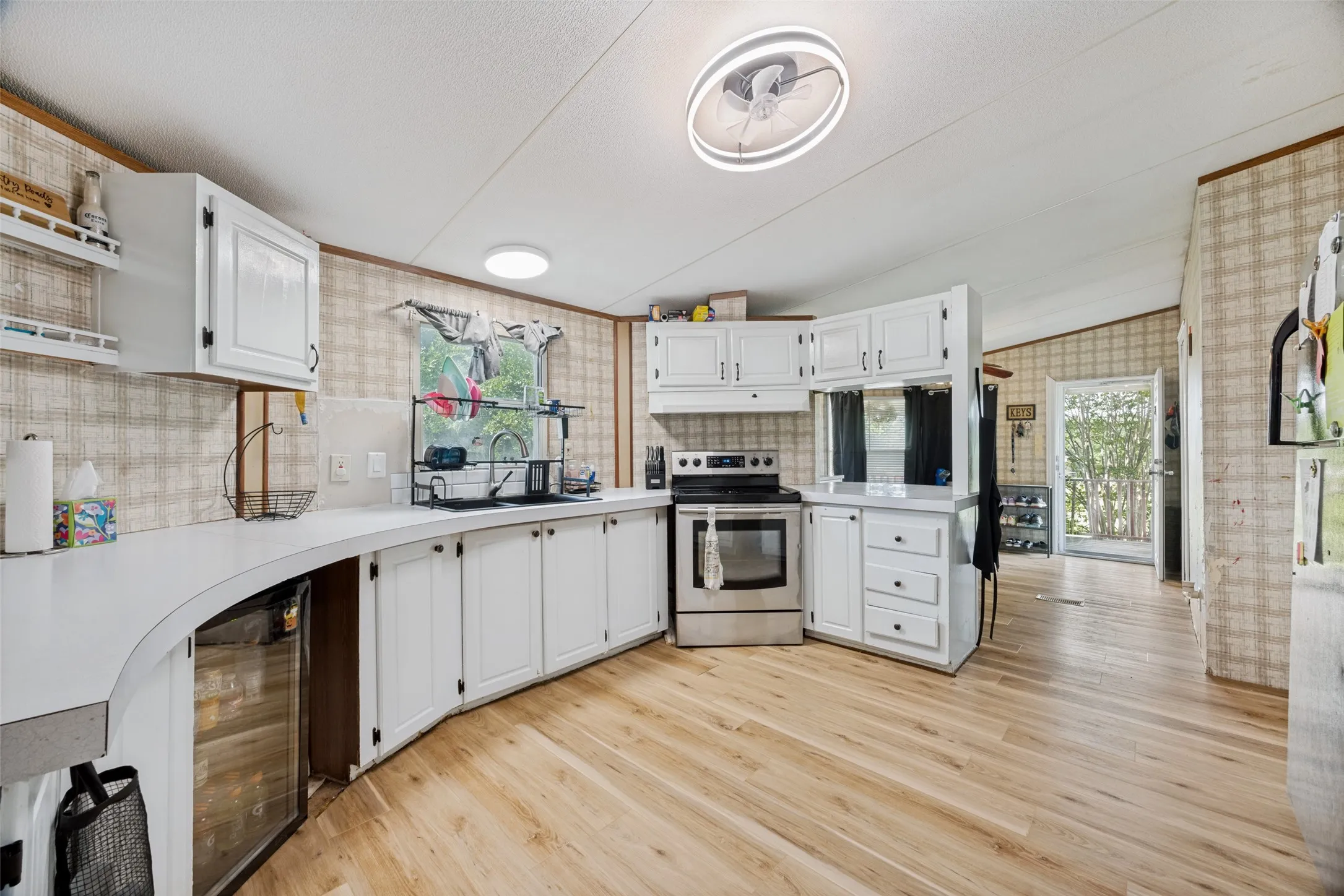 13x13 Kitchen featuring light wood-look smooth flooring, white cabinetry, and stainless steel appliances.  Updated sink, lighting and appliances.