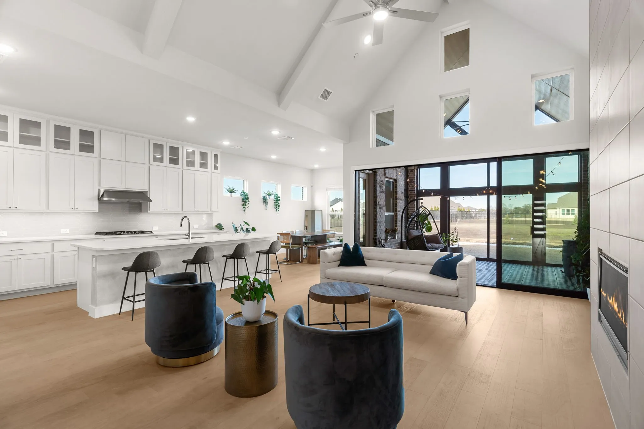 Living room with open floor plan, light wood flooring, and a high ceiling