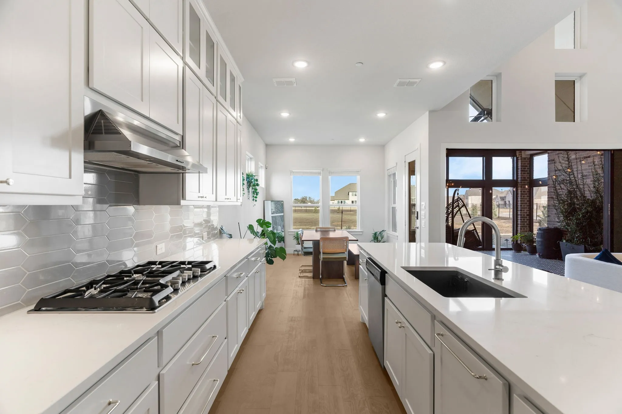Kitchen with stainless steel appliances, gas cooktop, backsplash, white cabinets, and sink