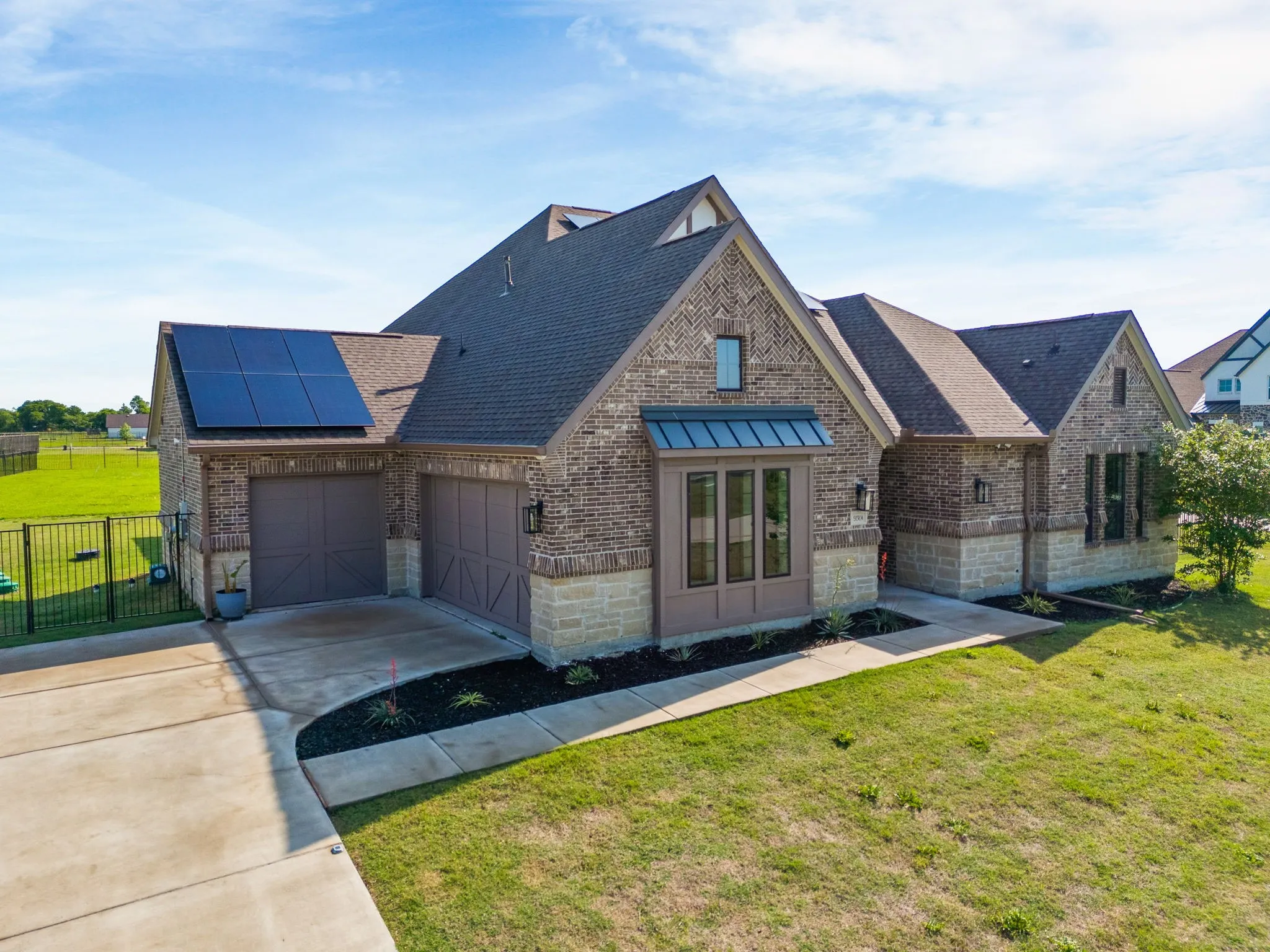 View of front of home with concrete driveway, solar panels, a front yard, and brick siding