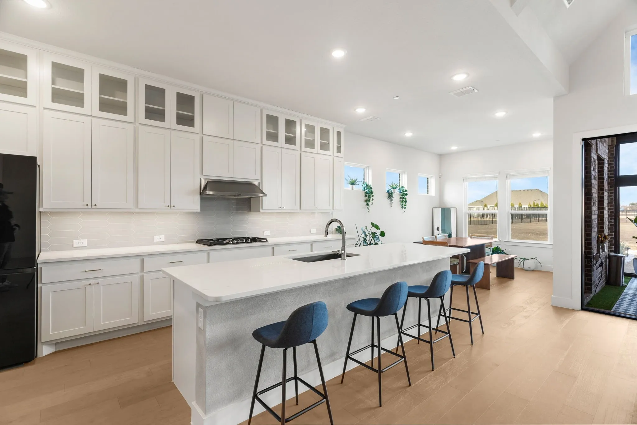 Kitchen with white cabinets, stainless steel gas cooktop, a kitchen bar, and a center island with sink