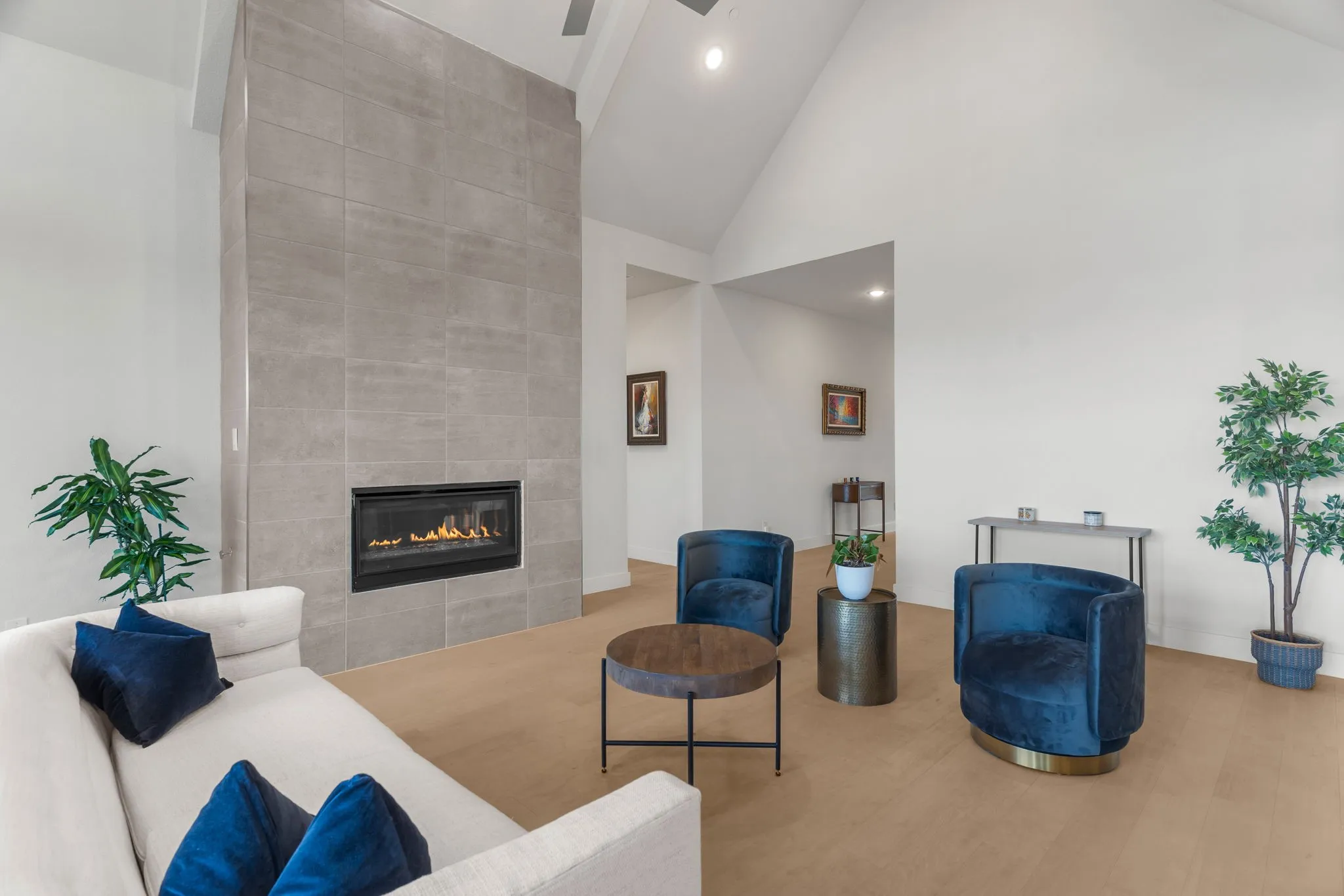 Living room with high vaulted ceiling, a tile fireplace, and wood flooring