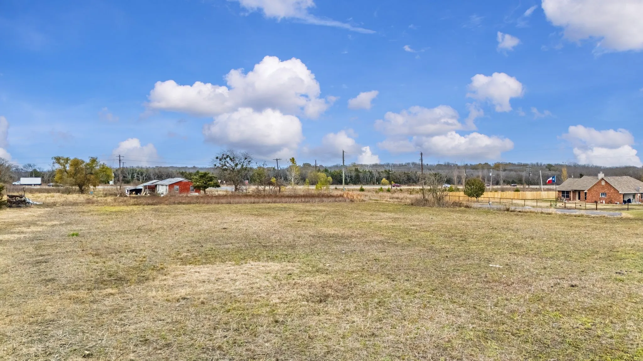 Expansive open field with scattered trees and distant structures