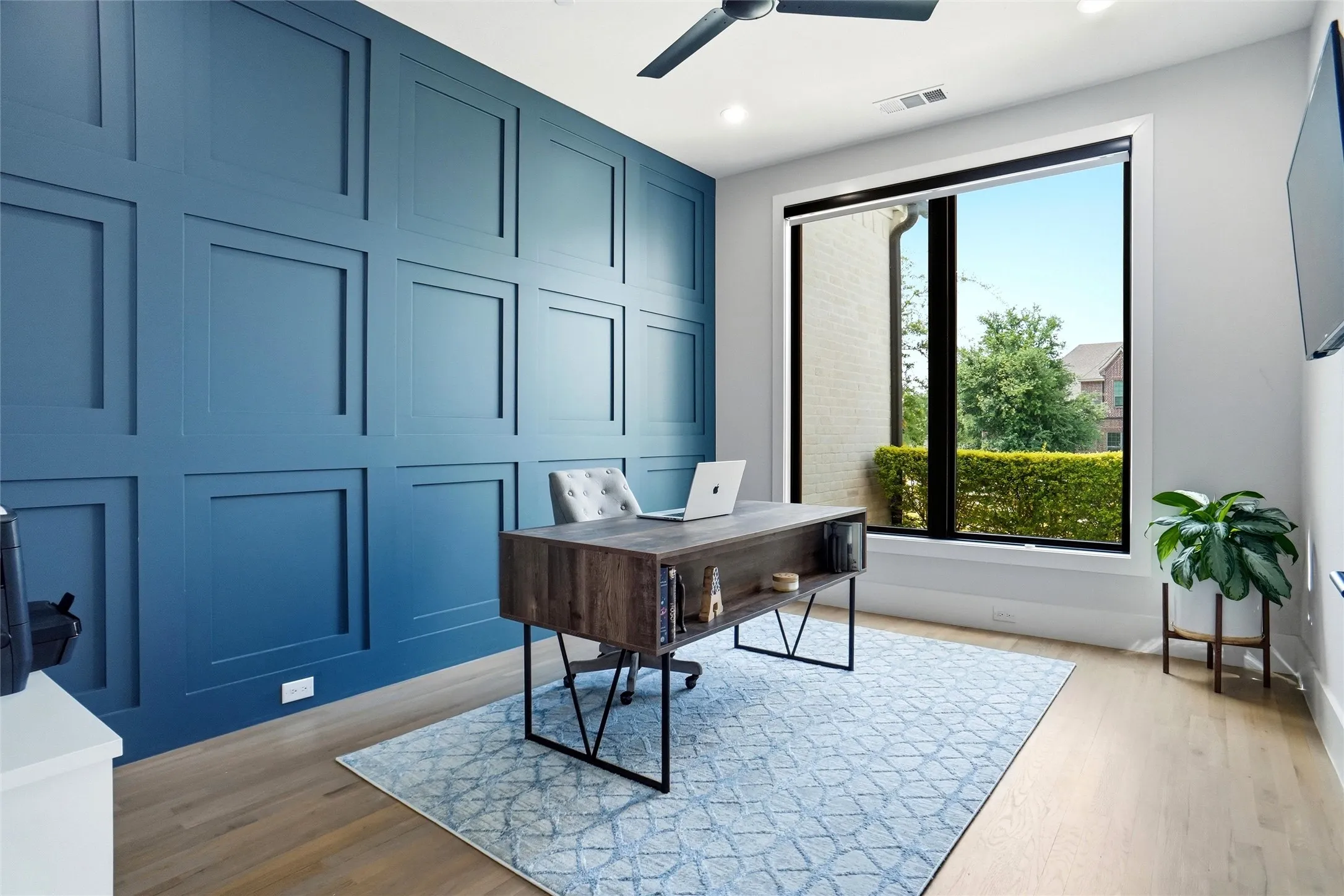 Room featuring a full wall of decorative paneling, light wood-finish flooring, and a large picture window