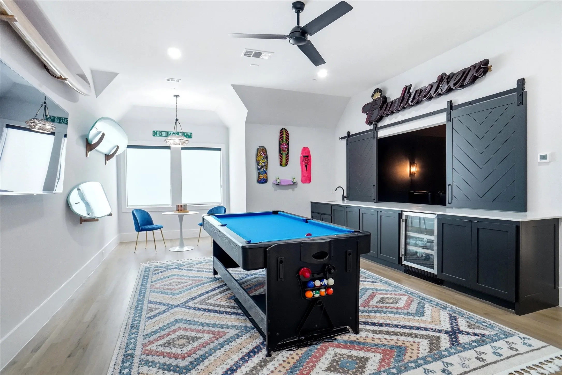 Spacious recreational room featuring a built-in entertainment center with barn doors, a beverage refrigerator, and an integrated sink