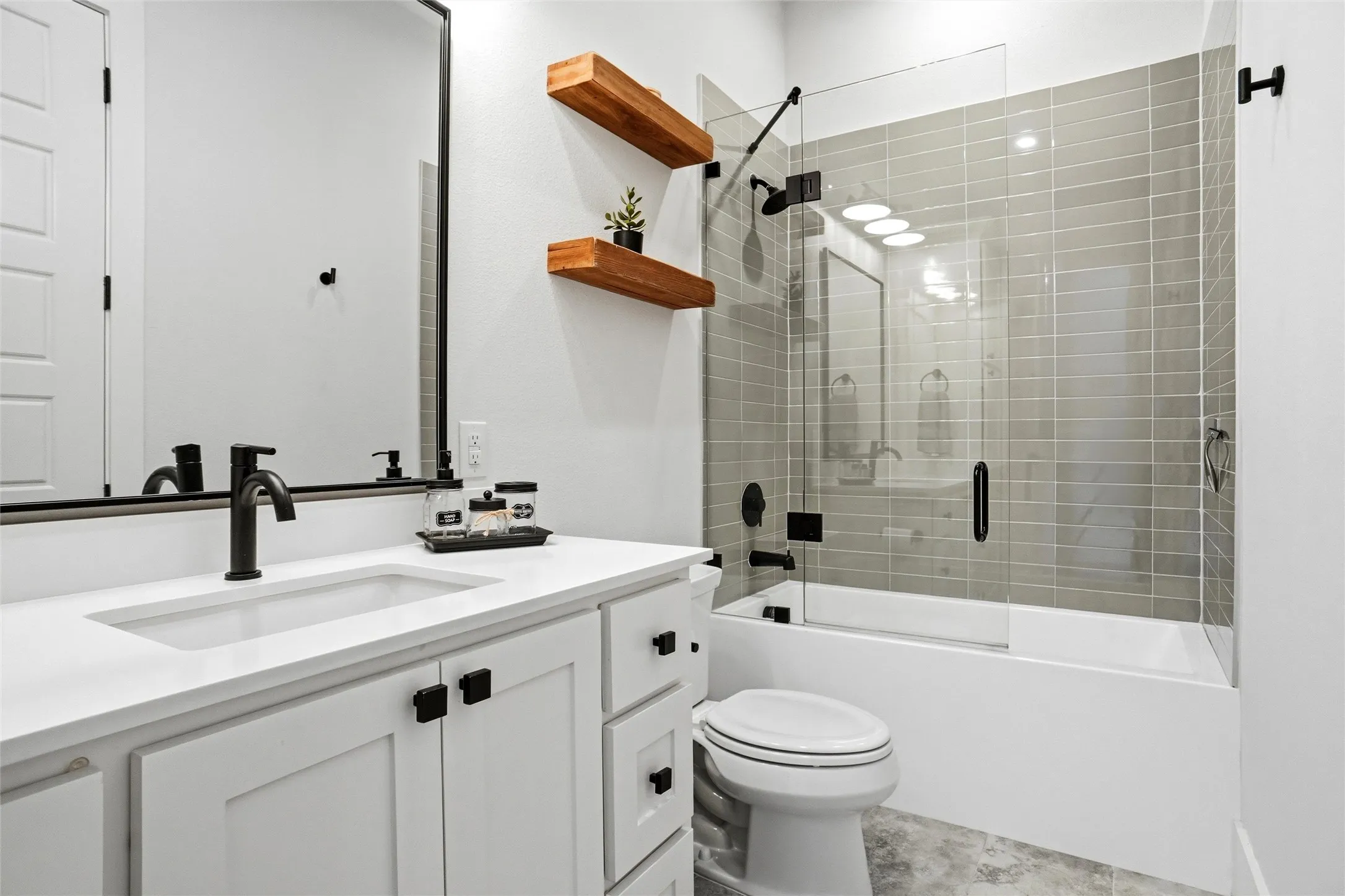 Modern bathroom featuring a white vanity with integrated sink, matte black fixtures, and a framed mirror
