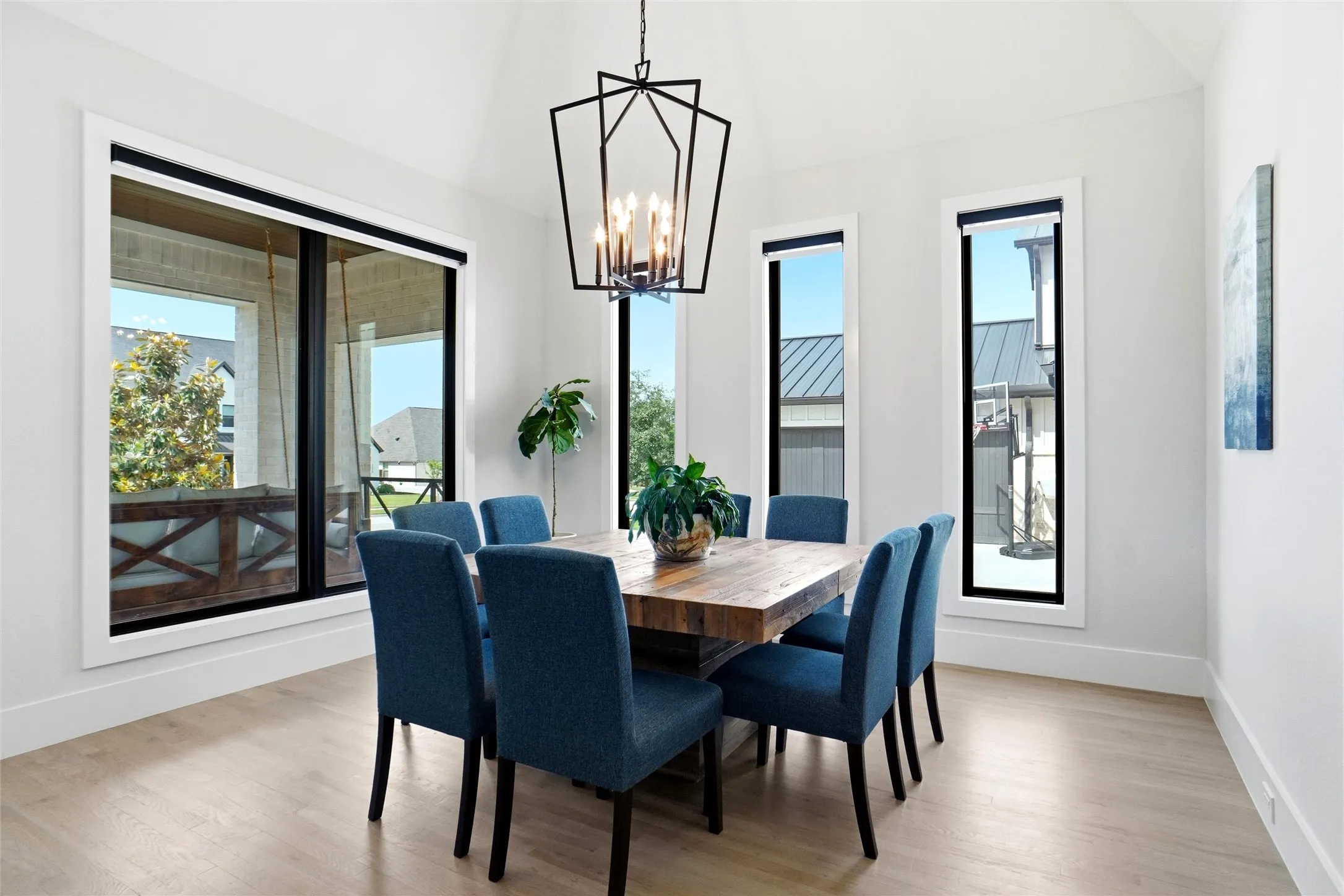 Dining area with vaulted ceiling, wood-finish flooring, and a large black geometric chandelier