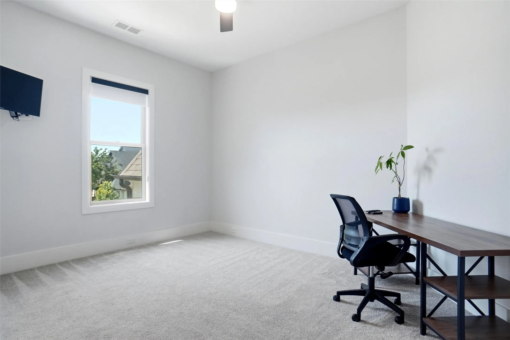 Carpeted room featuring a single window with white trim, a ceiling fan, and wall-mounted baseboards