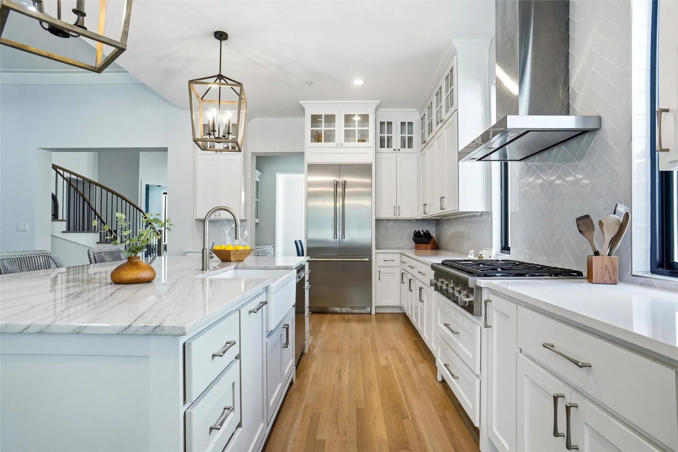 Kitchen featuring white cabinetry, wood-finish flooring, stainless steel appliances, a range hood, and a central island with a farmhouse sink