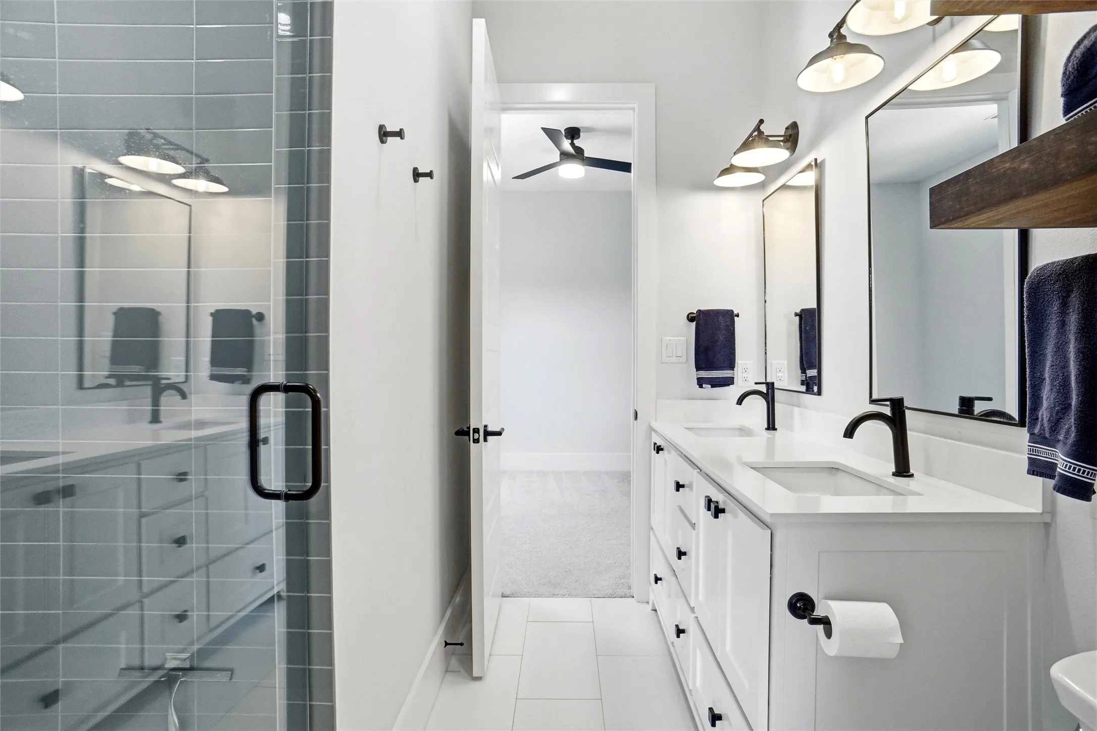 Modern bathroom featuring a dual vanity with white cabinetry, integrated sinks, and matte black faucets
