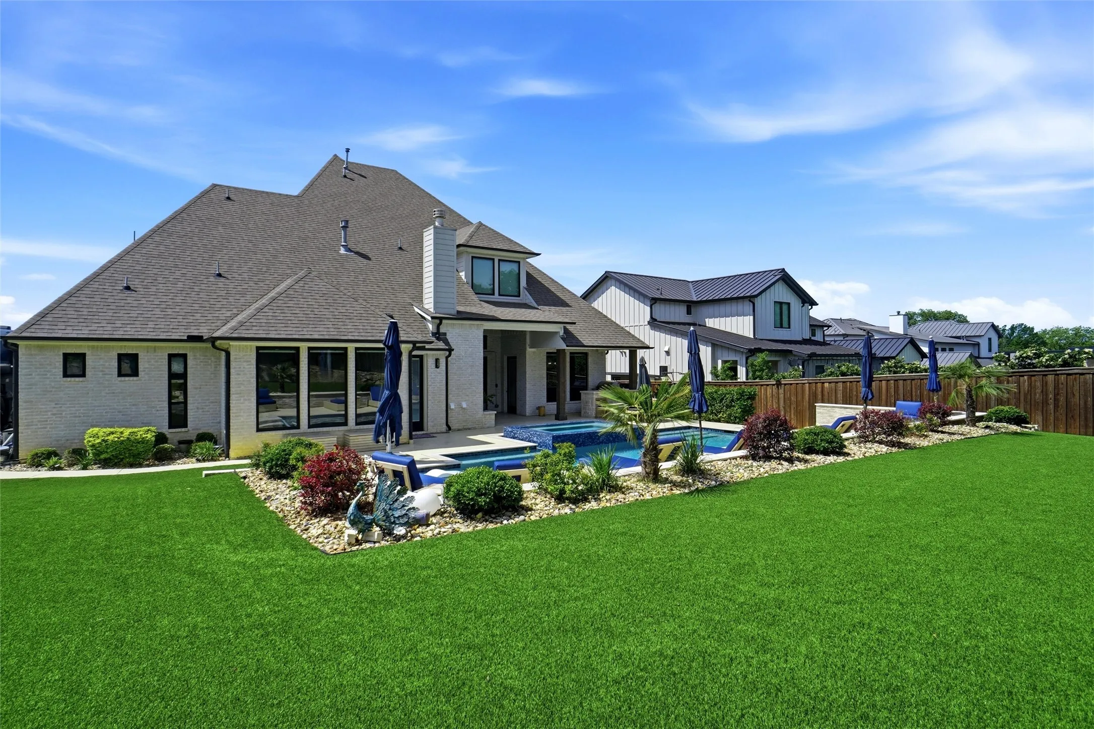 Expansive green lawn with a white brick exterior and dark roof