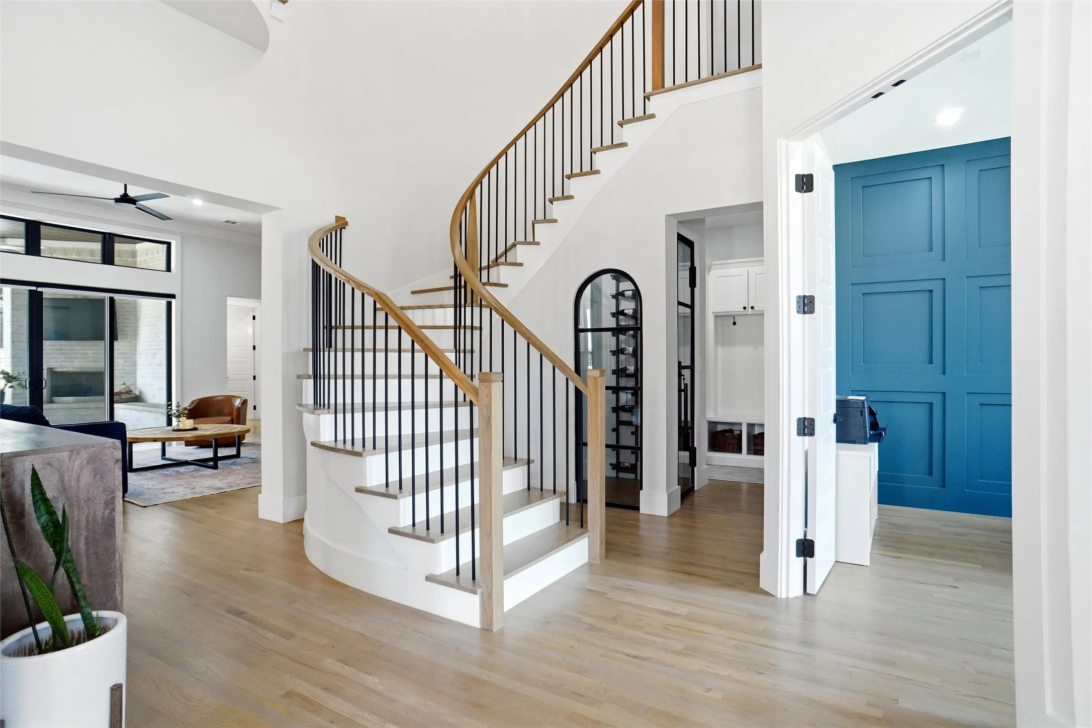 Curved staircase with wood-finish treads and risers, black metal balusters, and a light wood handrail