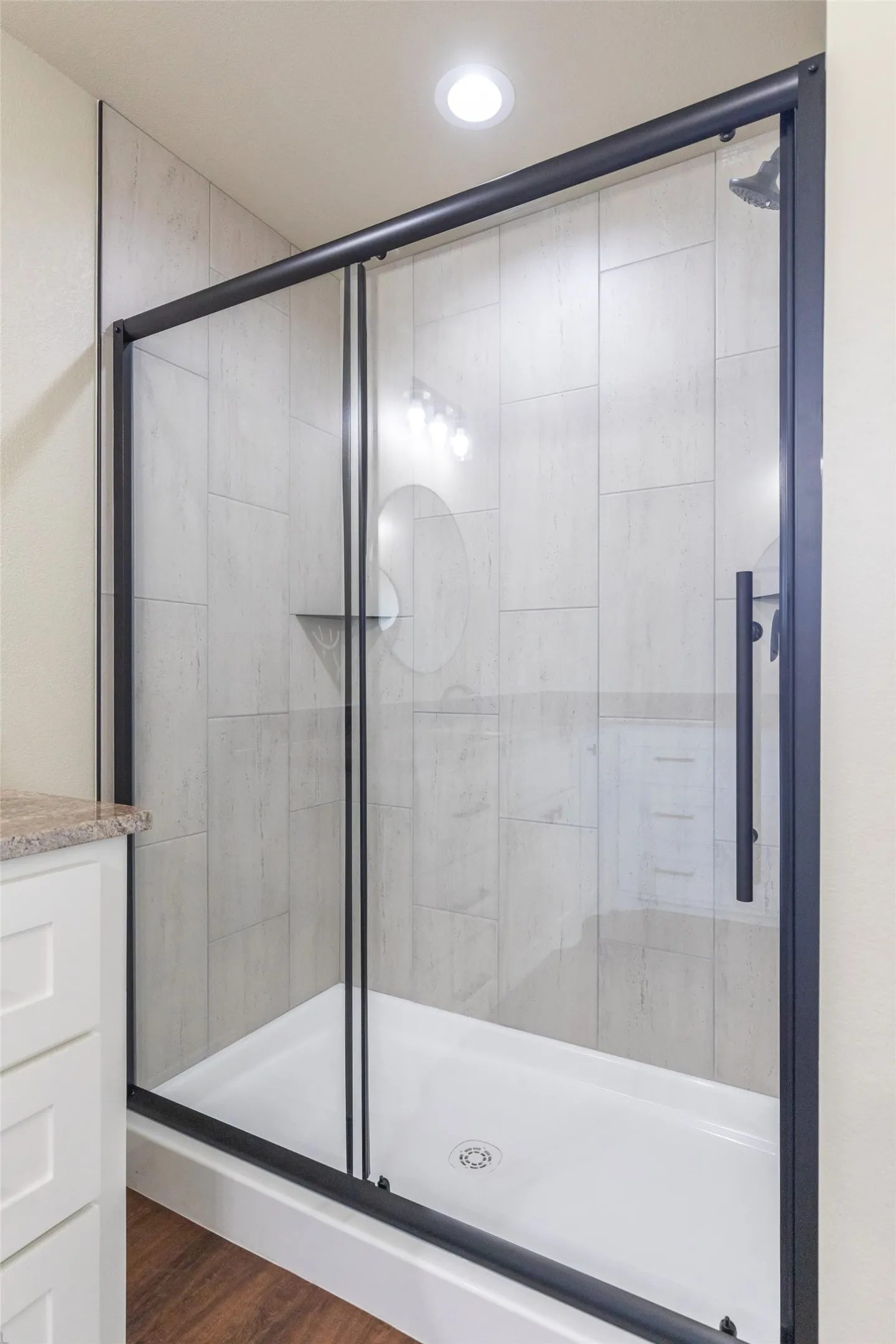 Shower enclosure with a matte black frame, clear glass panels, and a white shower pan