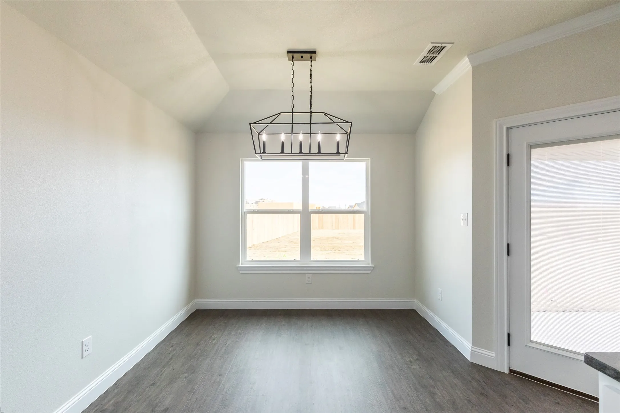 Open-concept room featuring wood-finish flooring, a contemporary geometric chandelier, and crown molding