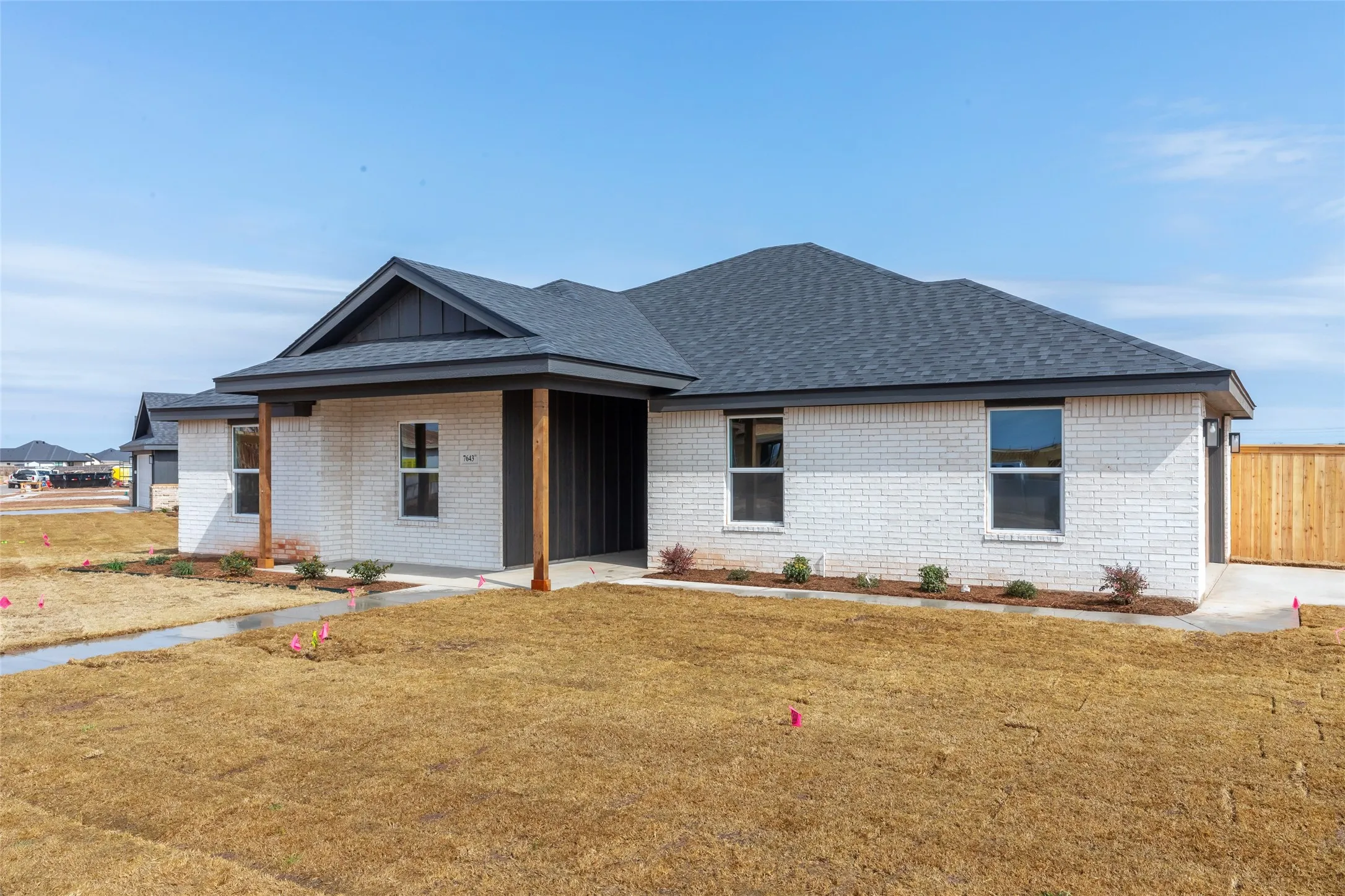 Contemporary ranch-style home featuring a white brick exterior and a dark gray shingle roof
