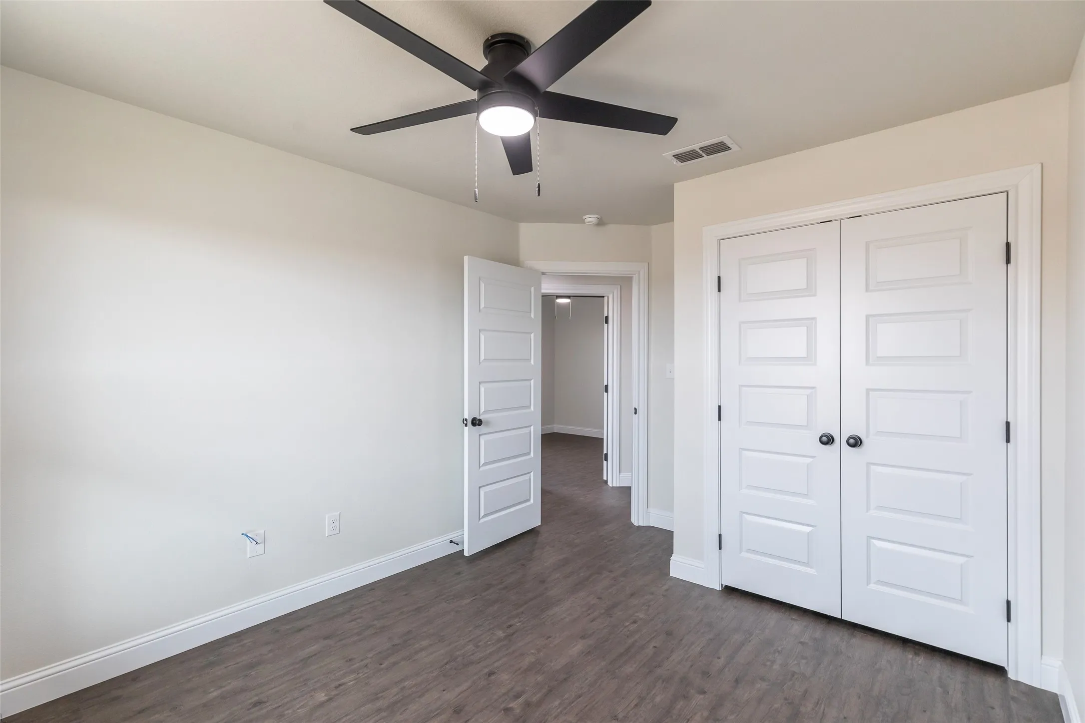 Room with wood-finish flooring, white walls, and a modern ceiling fan with integrated lighting