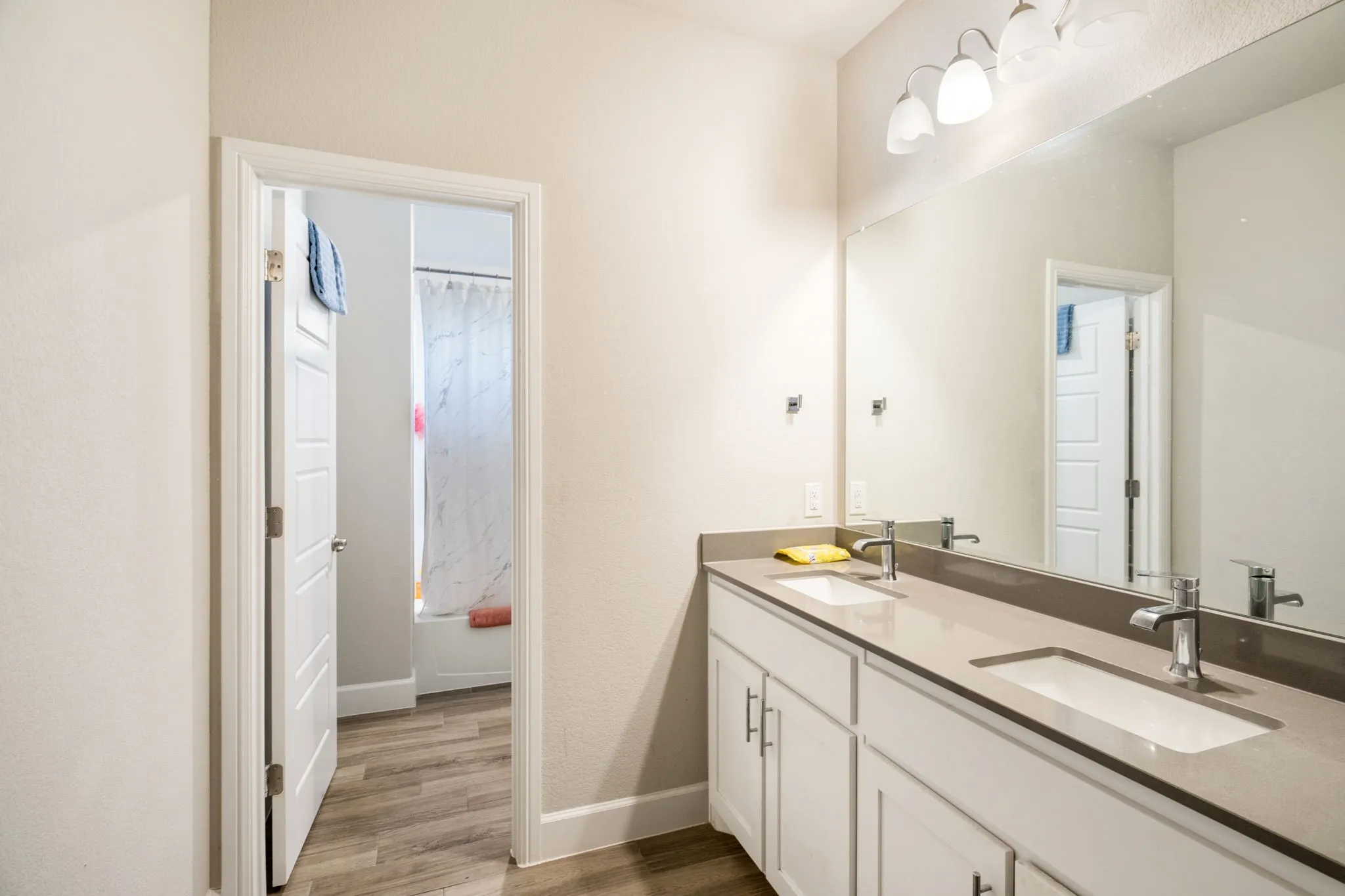 Contemporary bathroom featuring a dual vanity with light-colored countertops, undermount sinks, and chrome faucets