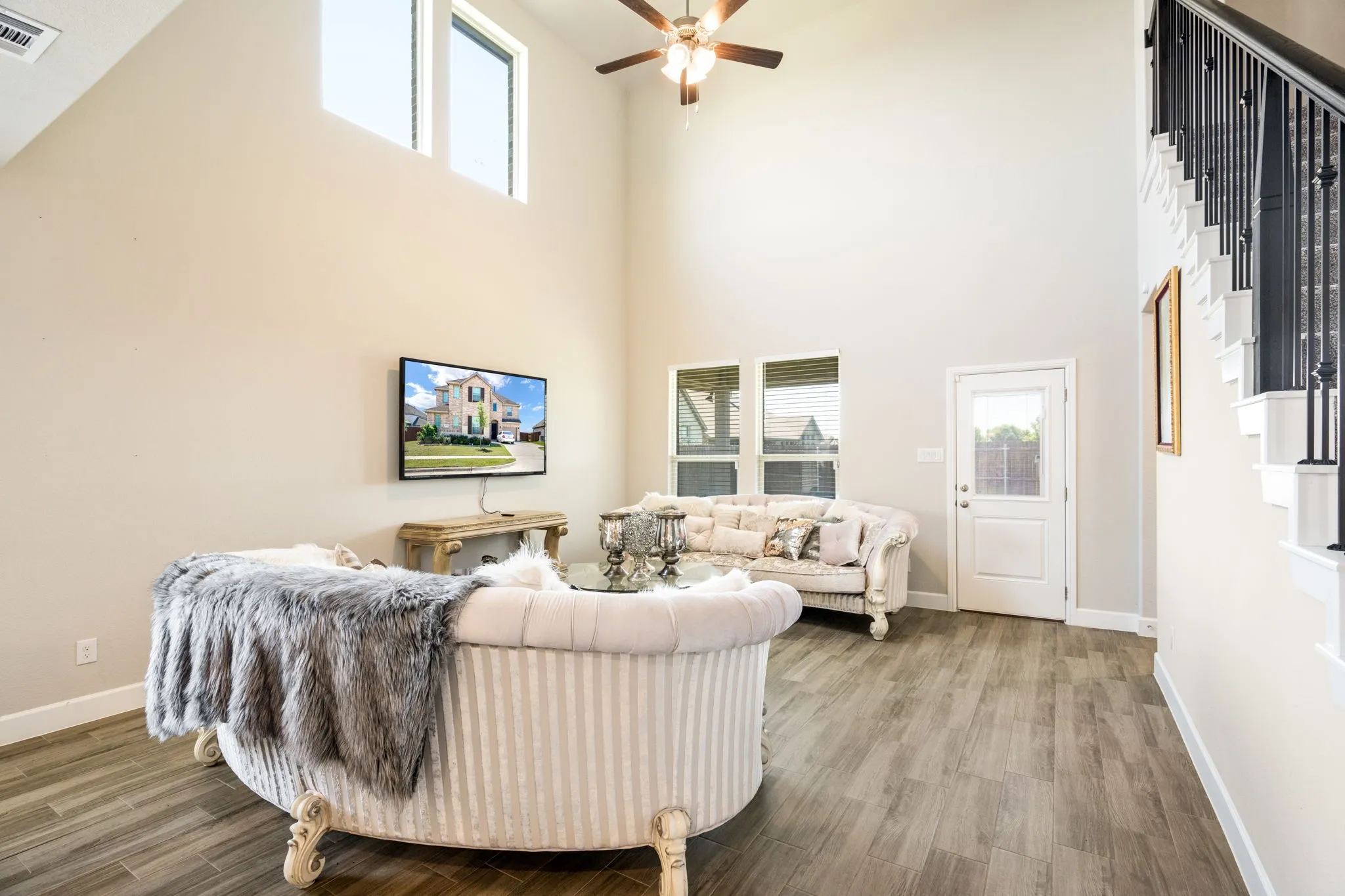 Living area featuring high ceilings, wood-finish flooring, and a ceiling fan