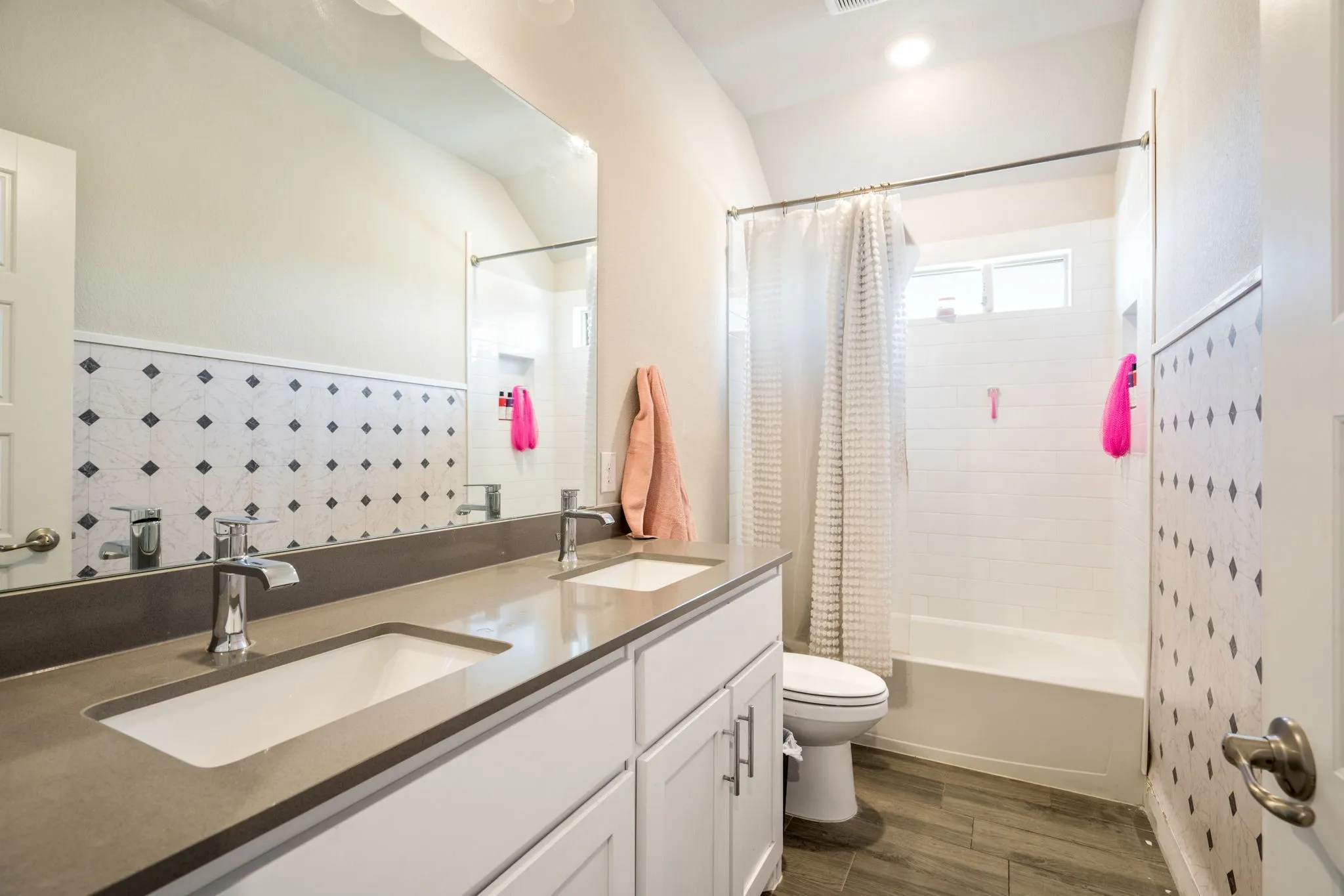 Bathroom vanity featuring a dual sink, integrated countertop, and white cabinetry