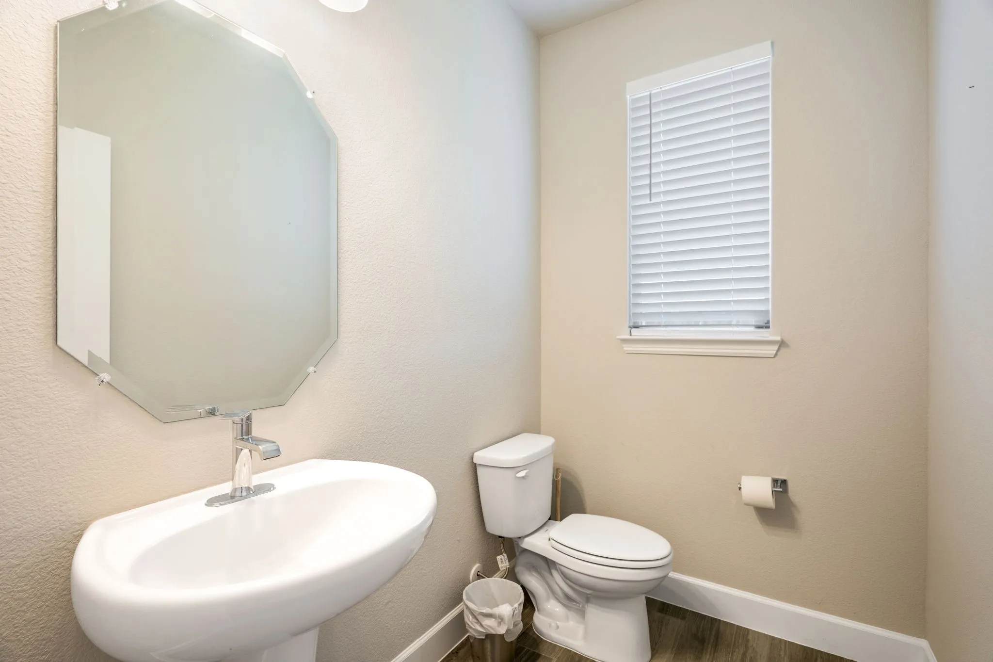 Pedestal sink with a polished chrome faucet and octagonal wall mirror