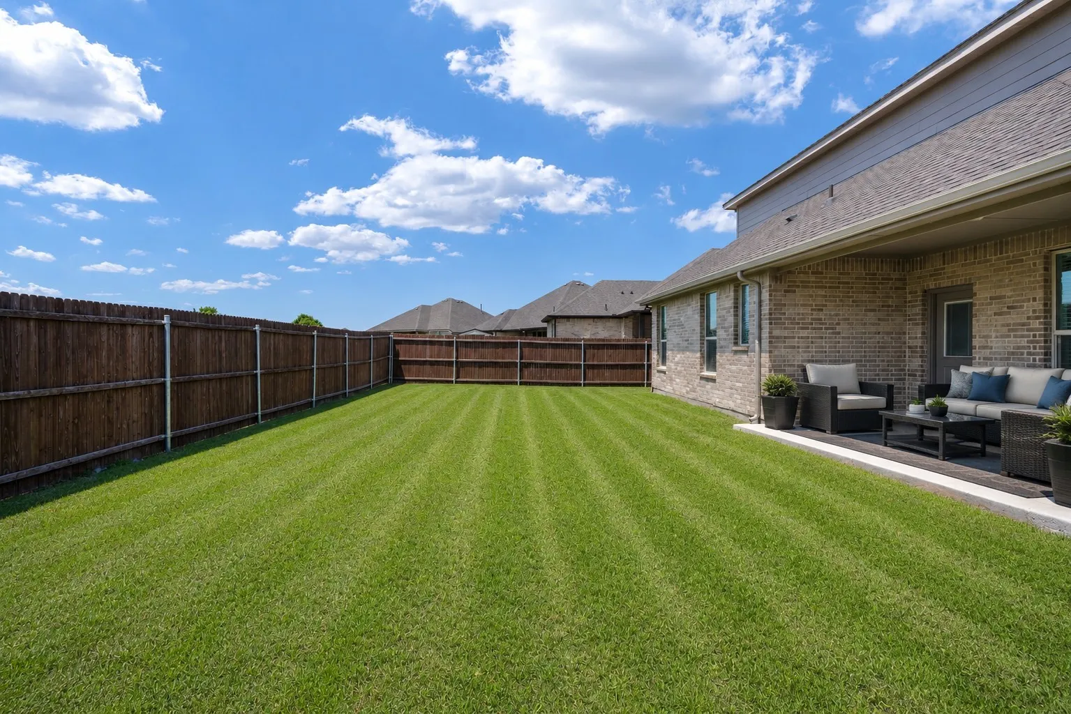 Expansive backyard featuring a wood privacy fence and a manicured lawn