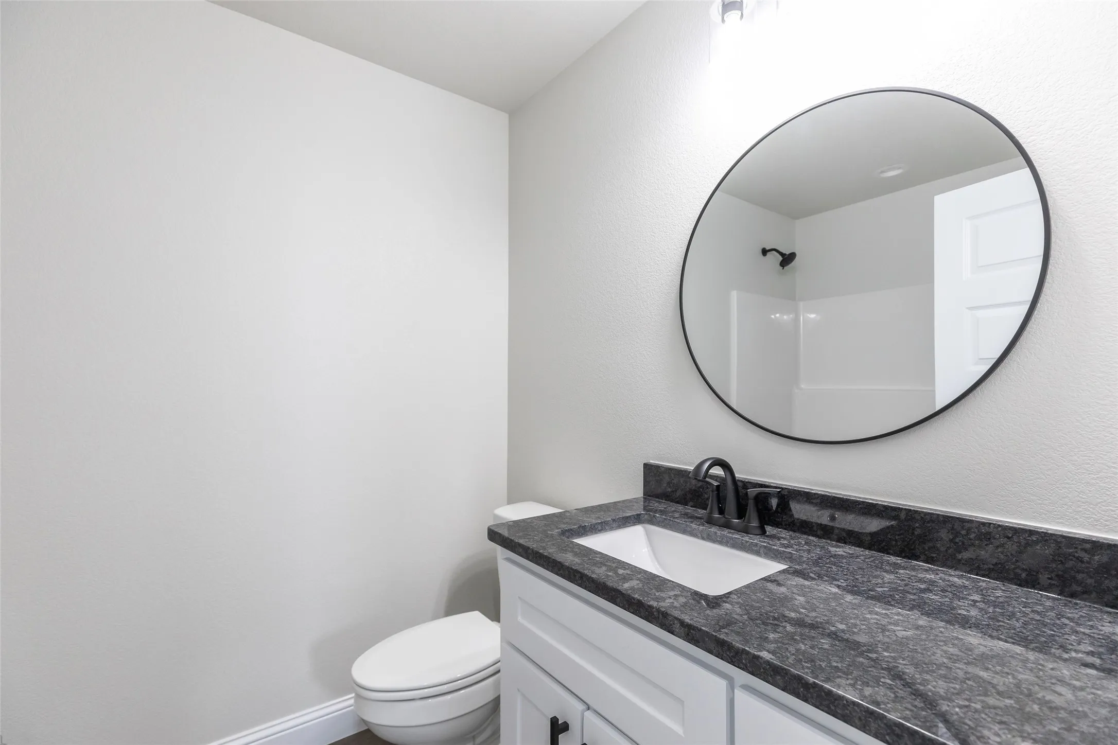 Bathroom vanity featuring a dark countertop, white undermount sink, and matte black faucet