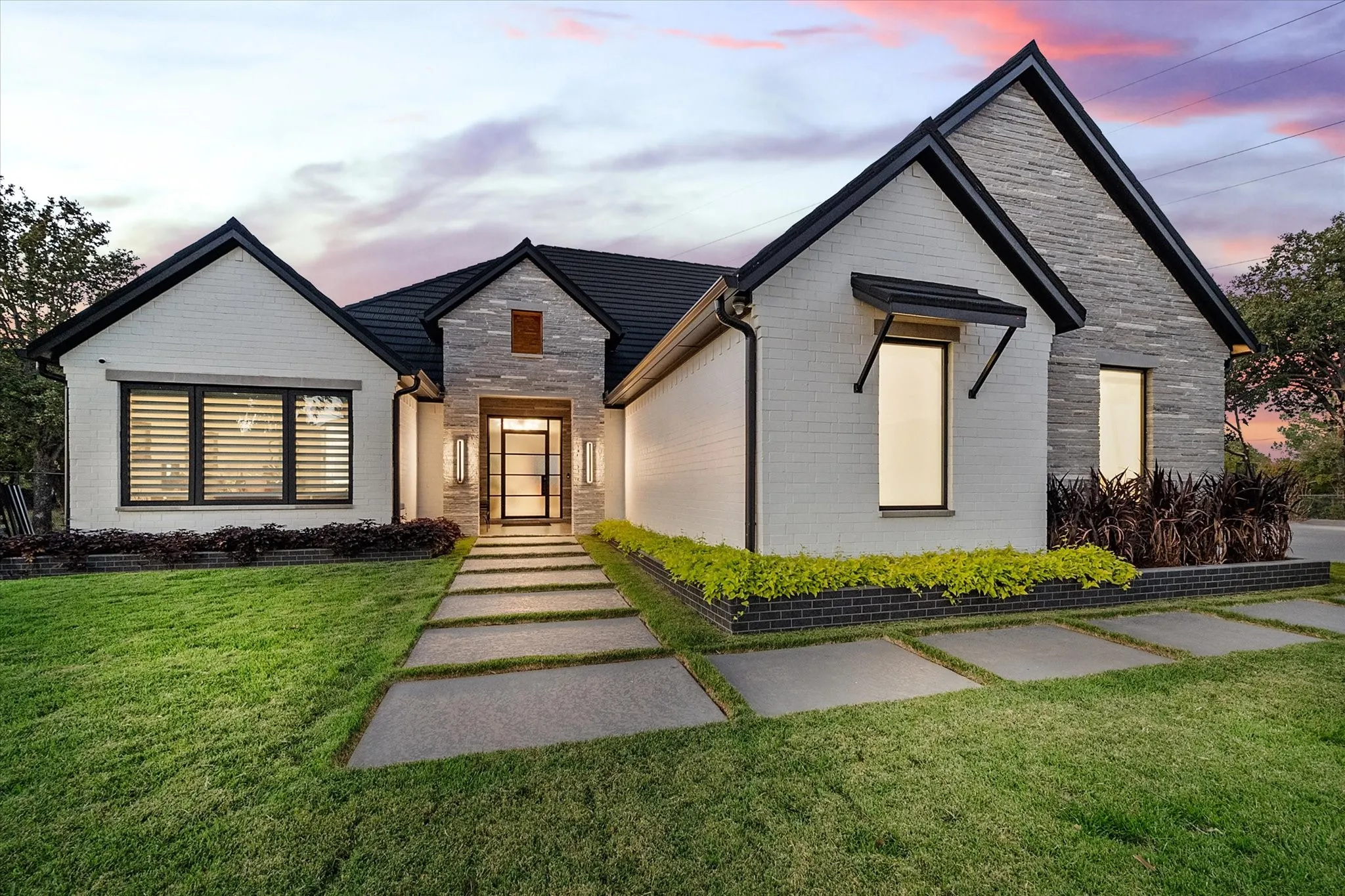 Contemporary exterior featuring white brick and stacked stone accents with modern square stone walk way