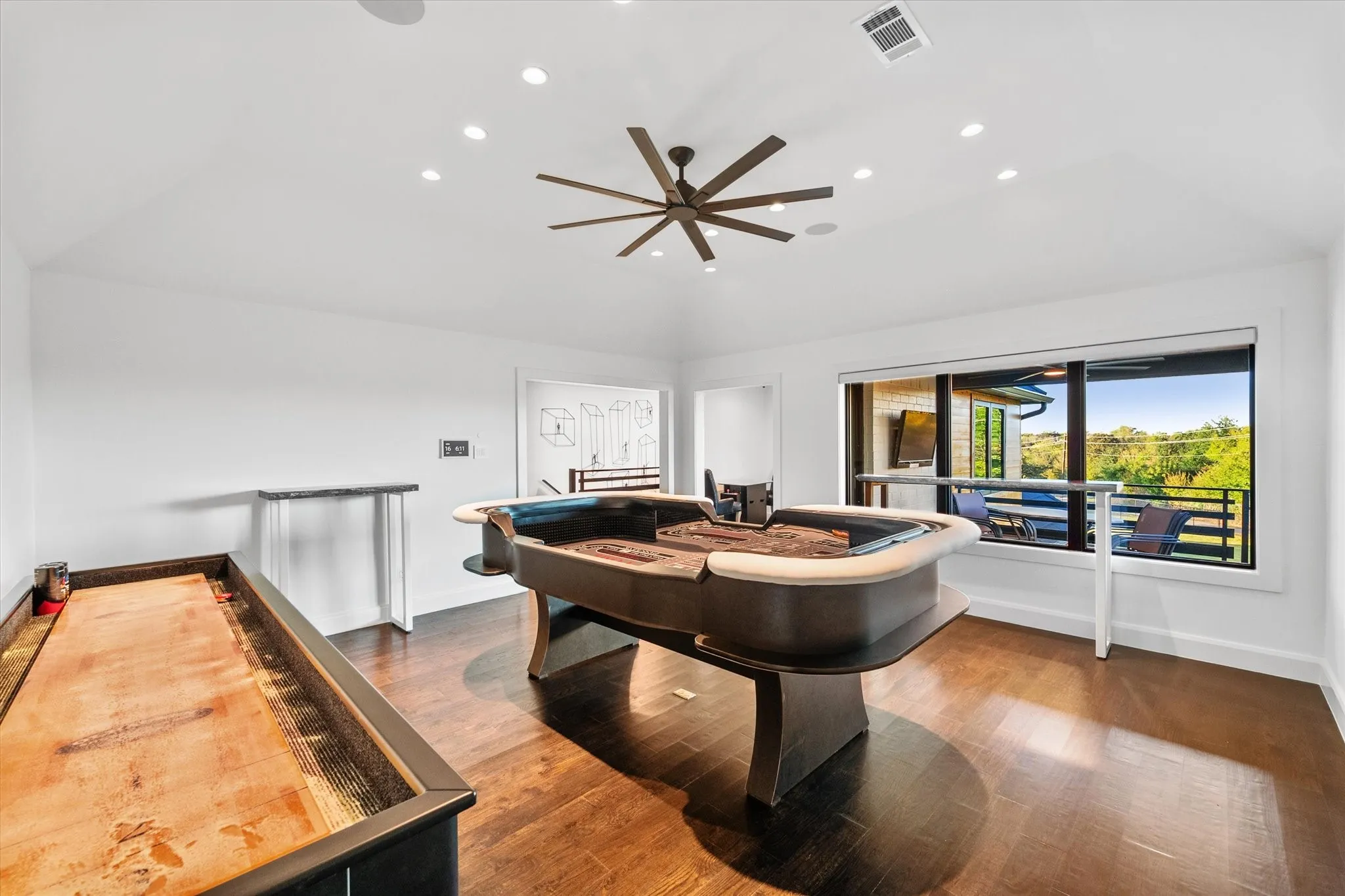 Spacious bonus room featuring wood-finish flooring, a vaulted ceiling with recessed lighting and a ceiling fan, and a wide window offering a landscape backdrop